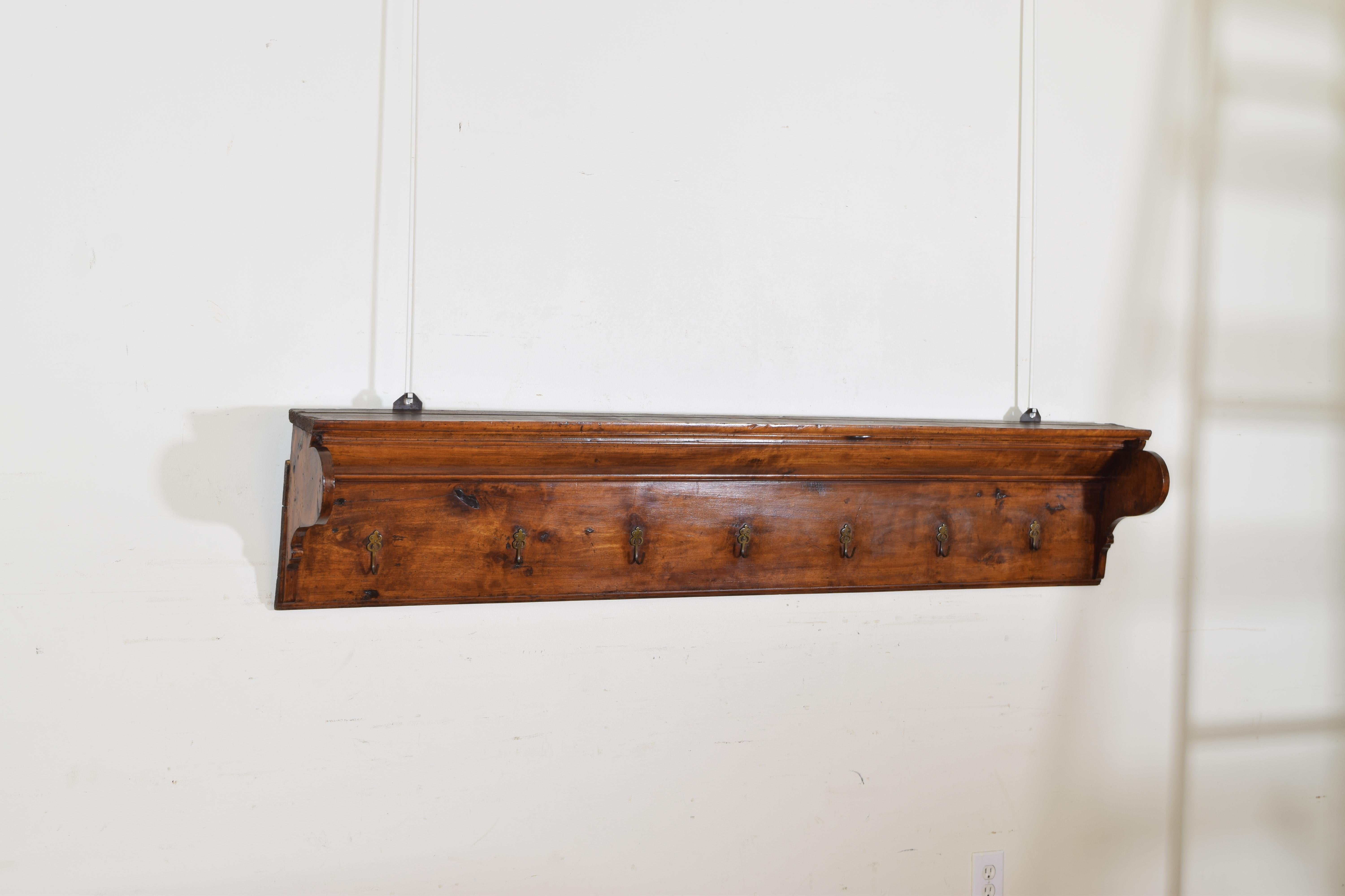 The upper flat surface with a channel for holding plates against a wall, the shaped sides flanking a molded vertical section, the lower portion with seven decoratively cast brass hanging hooks.