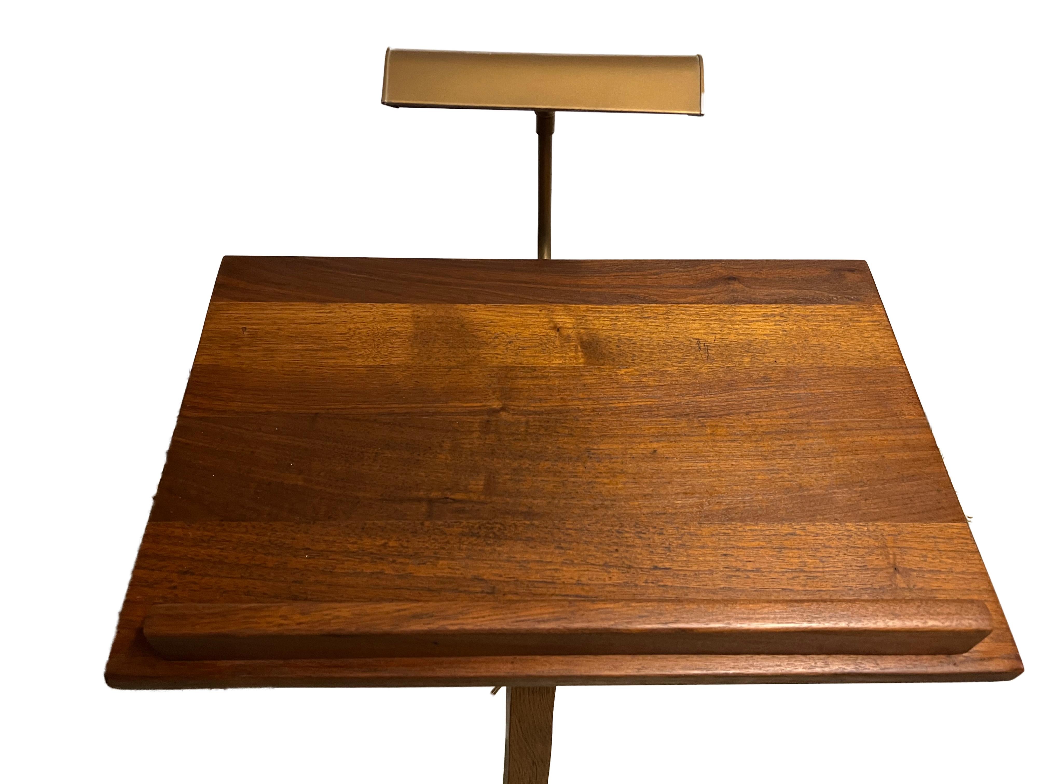A very fine quality piece, the stand has an upright column that carries an inclined walnut table top, with a concealed book rest and a brass light.
The tabletop cannot be adjusted.

This handsome Music Stand would also be a useful piece to hold