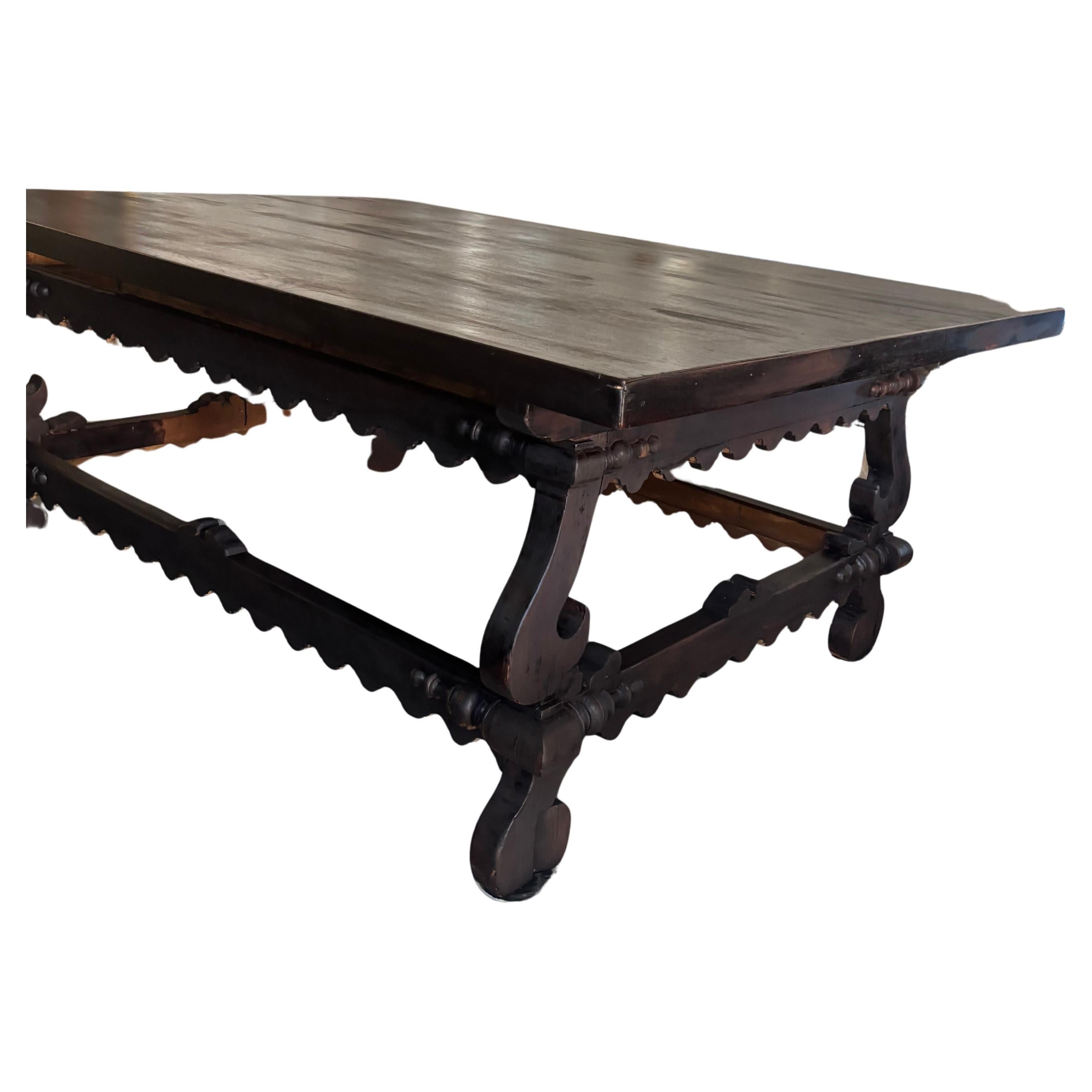 Stunning oversized handmade Jacobean dining table in darkest brown. The top is removable ⁢& sits on a base of walnut & pine.
The base has inverted legs joined by a box stretcher. The apron & base are edged with beautiful scalloped trim.