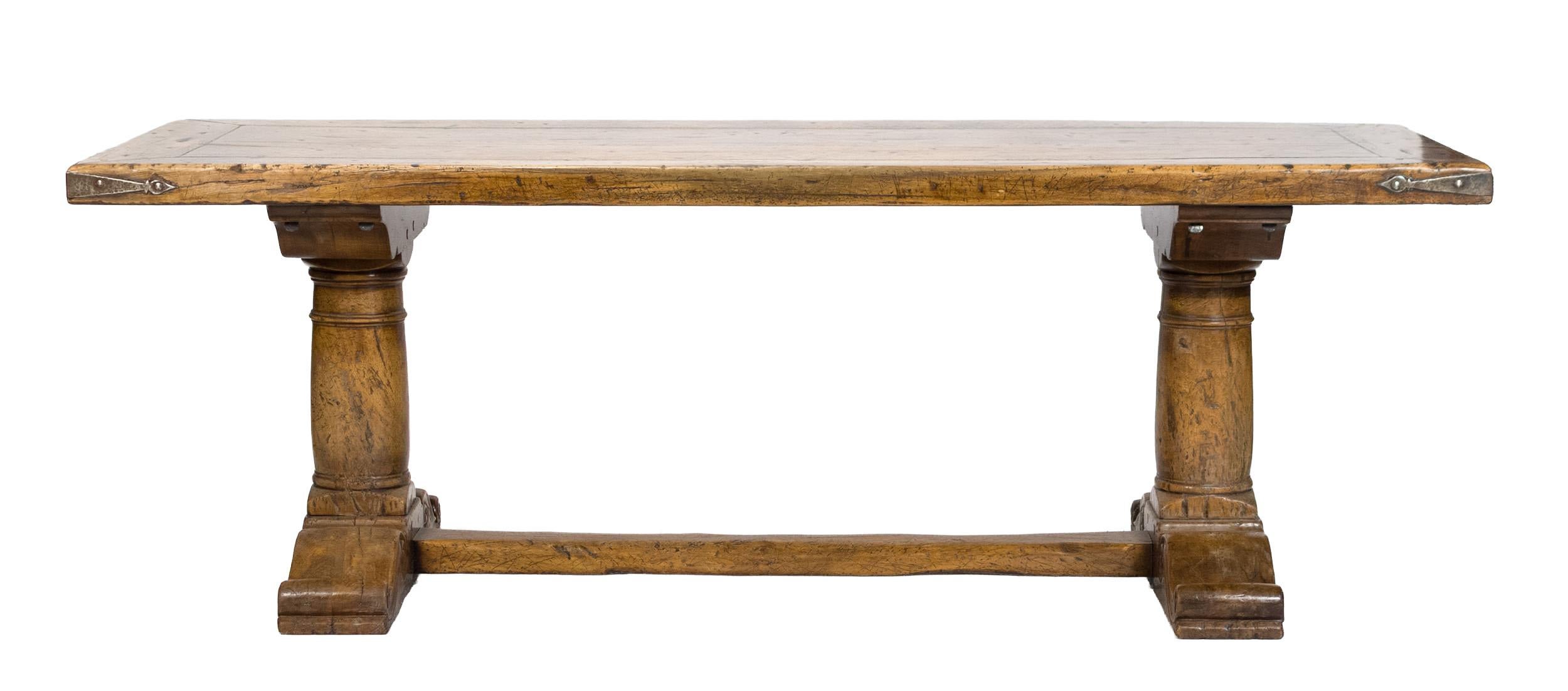 An exceptional 18th-century French walnut refectory table is in very good condition. The table features a substantial walnut slab top, supported by a double pedestal base. The feet are intricately carved in the scroll shoe style, and the lower