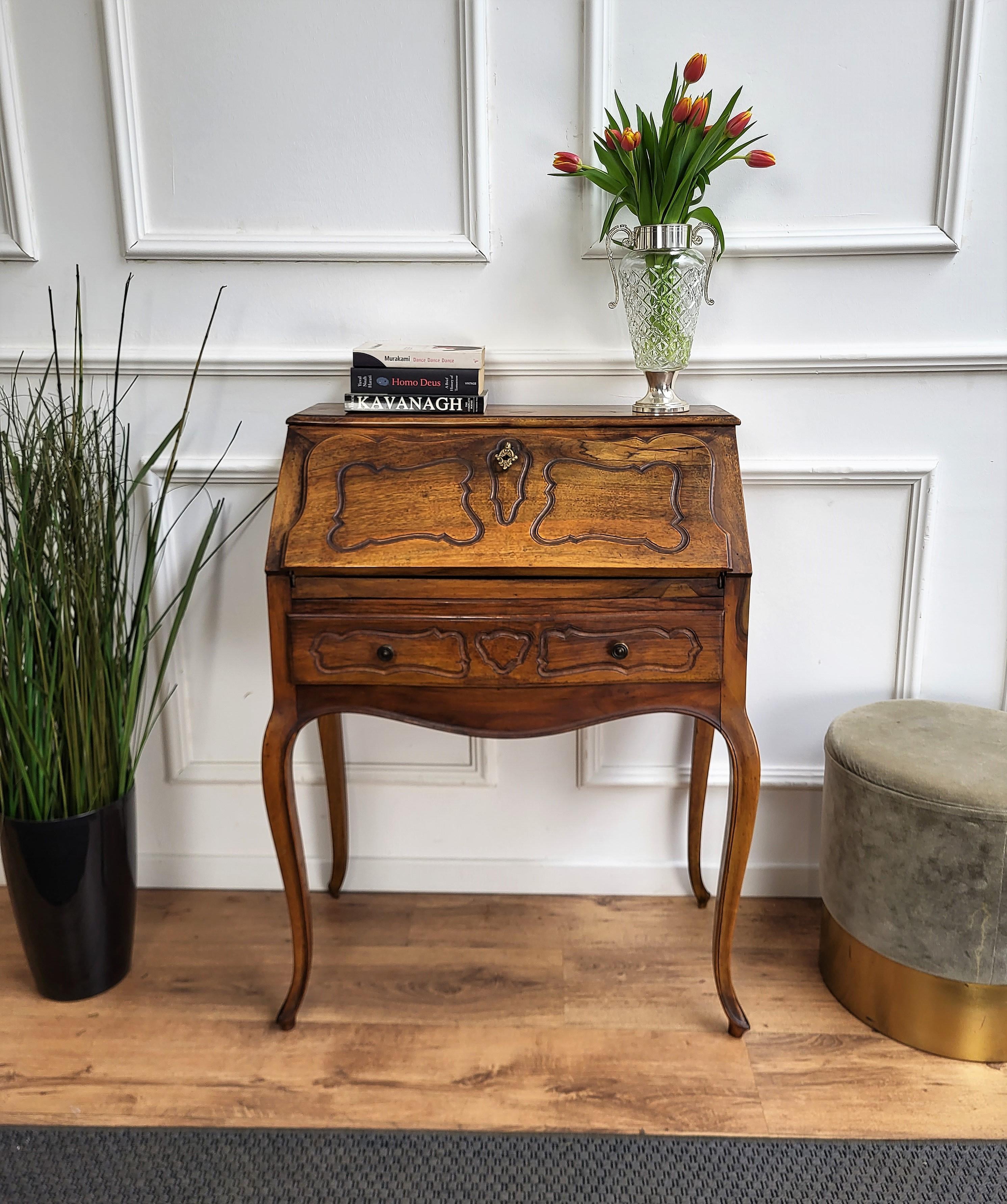 Very elegant desk, writing table, with slant drop front, with the beautiful carved decors in Classic figures all around the piece and saber legs. When opened we find the writing area with four drawers and a central door, all detailed with brass