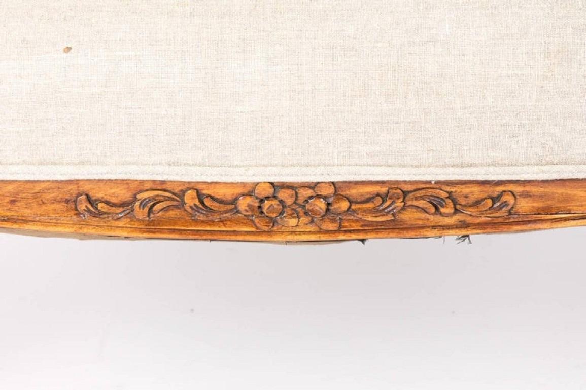 French walnut settee with beautiful floral carvings, made in a Rococo revival style circa 1900. The traditional Louis XV style here is streamlined and modernized with subtle Art Nouveau flair, seen in the scrolling armrests. A typical sofa