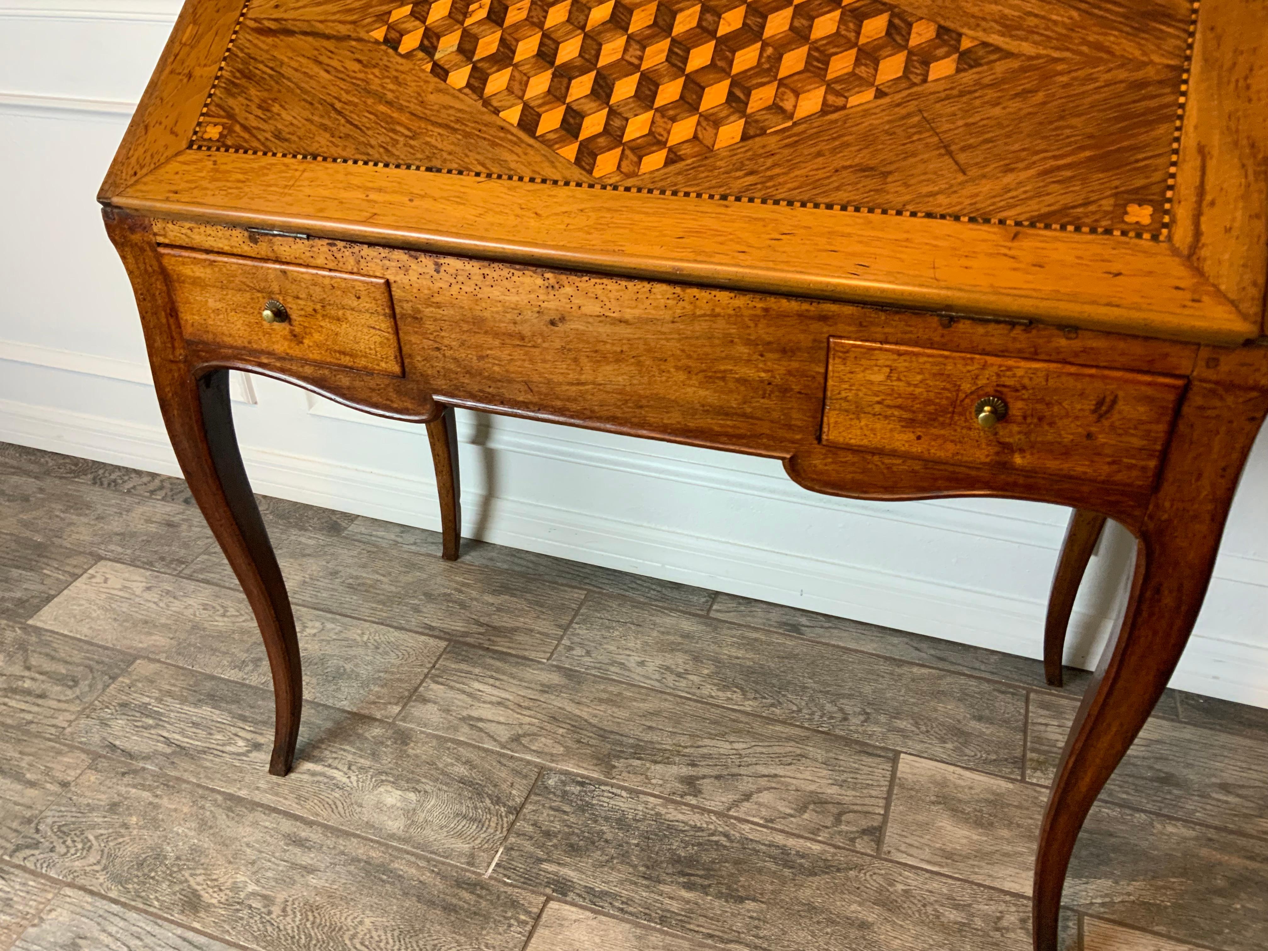 A very attractive late 18th century French Walnut slant front desk with geometric marquetry design on the lid.  Gold tooled leather writing surface on the inside of the lid over two drawers on the cut out apron.  One drawer on the inside reveals a