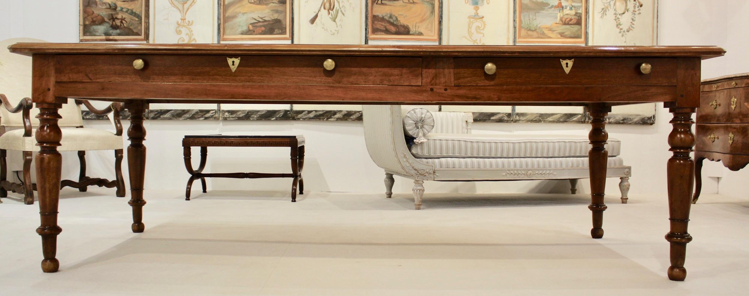 A gorgeous table in walnut from circa 1840 with a fabulous patinated top resting on four solid turned feet in Louis Philippe style. Two very large and deep drawers on one side with Brass pulls and key holes.
It can be a conference or dining table.