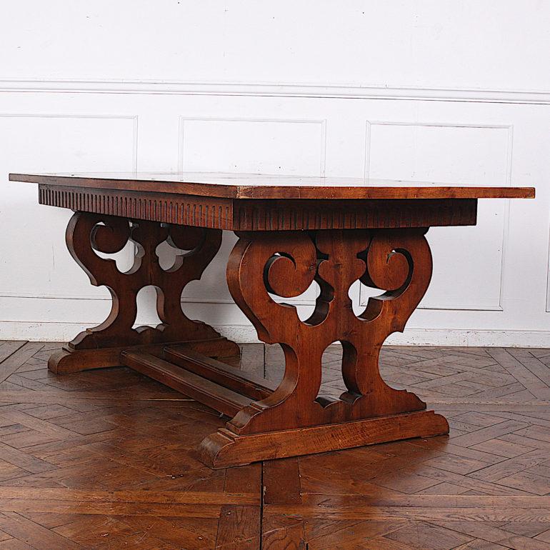 An early 20th century French parquet top walnut trestle table with dramatically-shaped end supports joined by a double stretcher. 
 
