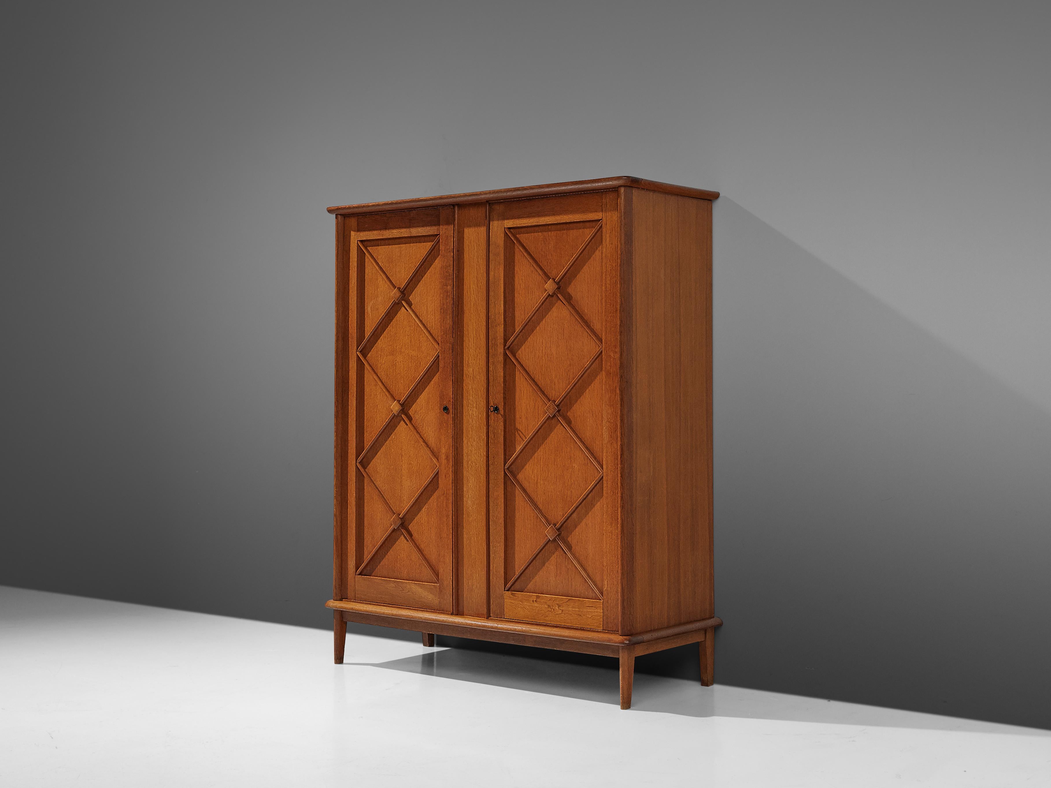 Wardrobe, oak, France, 1960s.

An elegant wardrobe in oak that features geometric details in the doors. Round slats with accentuated midpoints decorate the two doors. The inside is structured in two compartments. On the left a clothes rail is