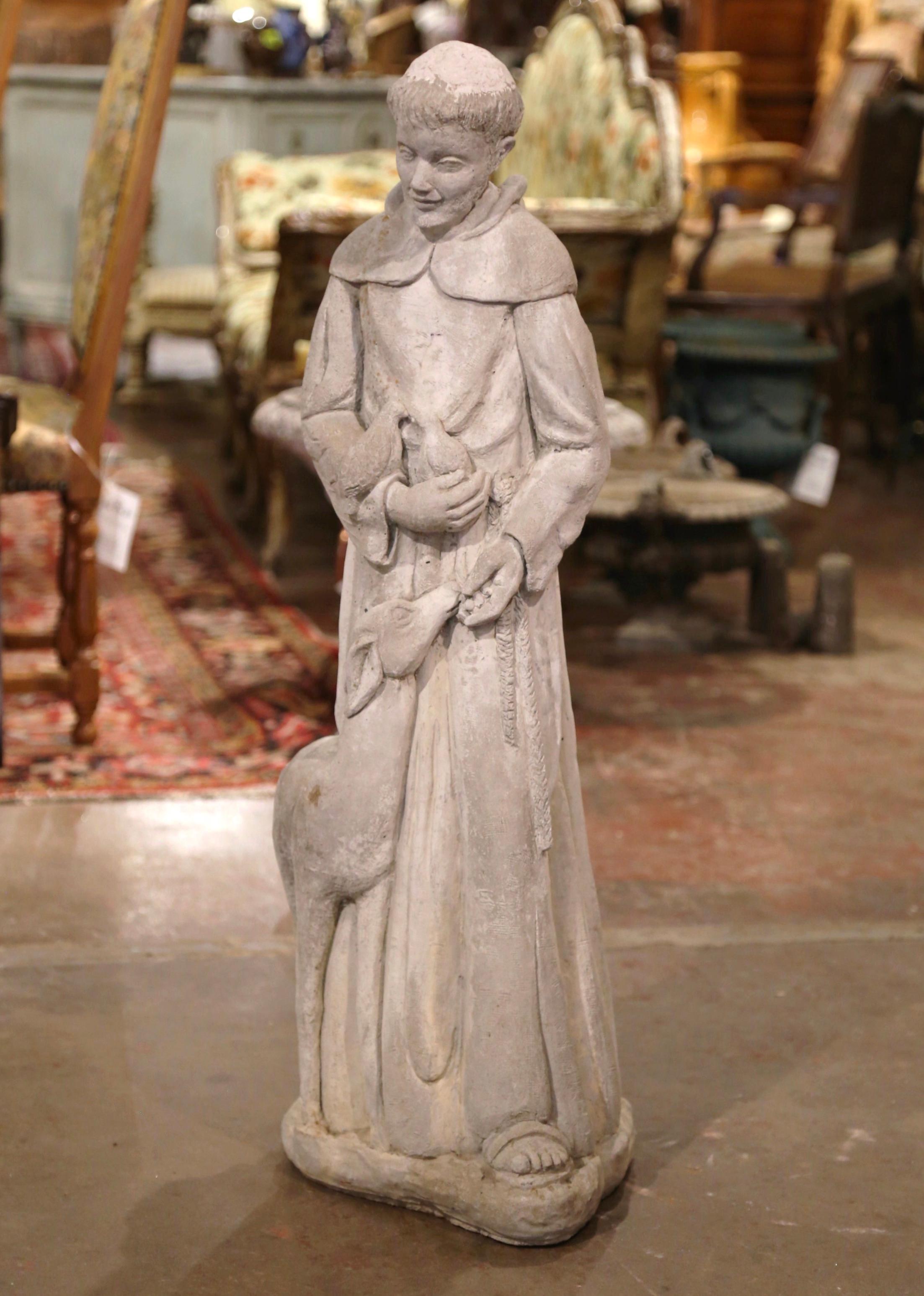 Decorate an outdoor garden with this antique statue featuring Saint Francis, the saint patron of animals. Crafted in France, the carved vintage statue depicts the Saint dressed in cassock, holding two birds in one hand while feeding a lamb with the