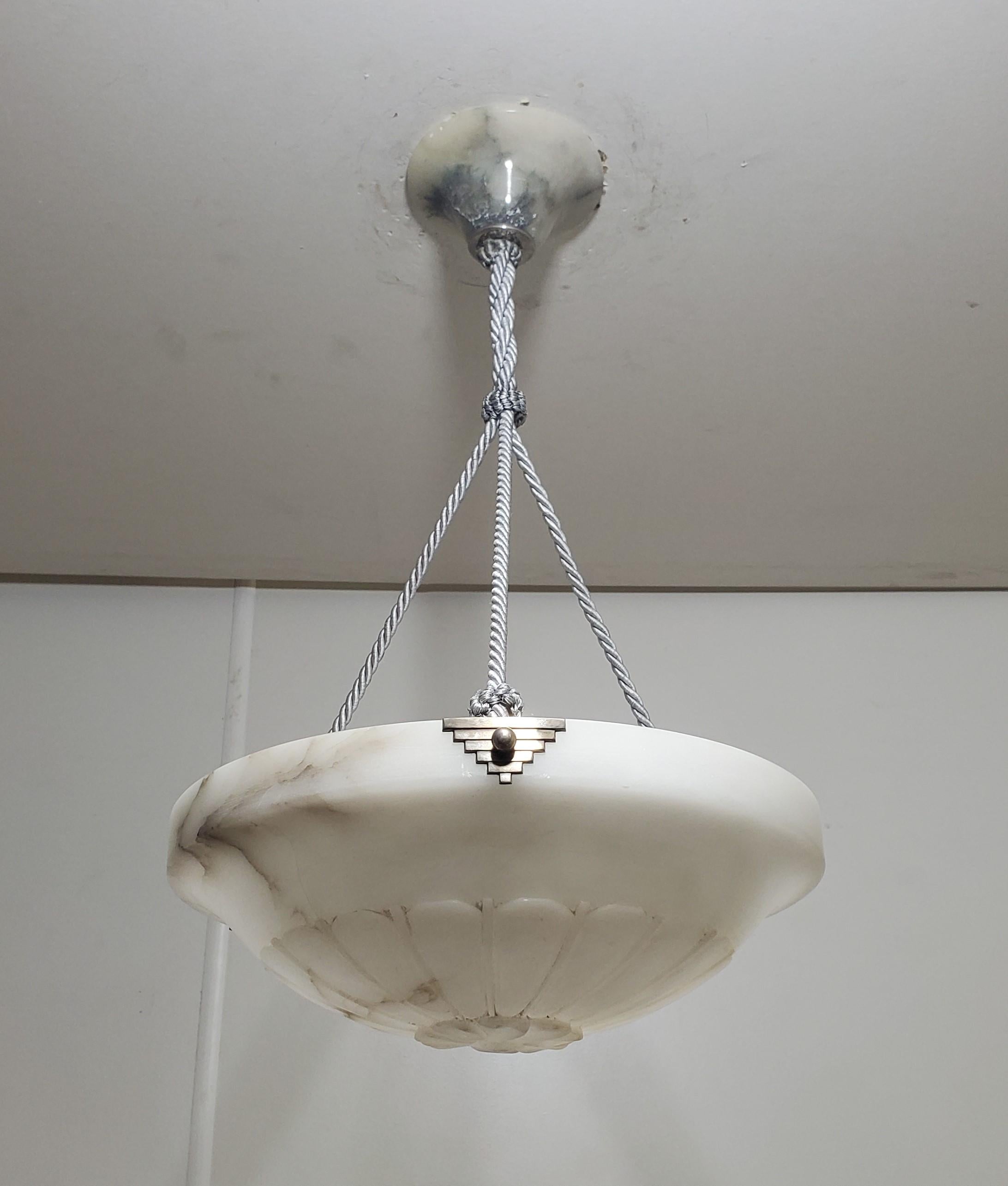 Una lampada a sospensione originale in alabastro e corda grigia progettata e prodotta in Francia, negli anni '30 circa.
Questo lampadario Art Deco francese a forma di ciotola in alabastro presenta una distinta striatura naturale di colore grigio