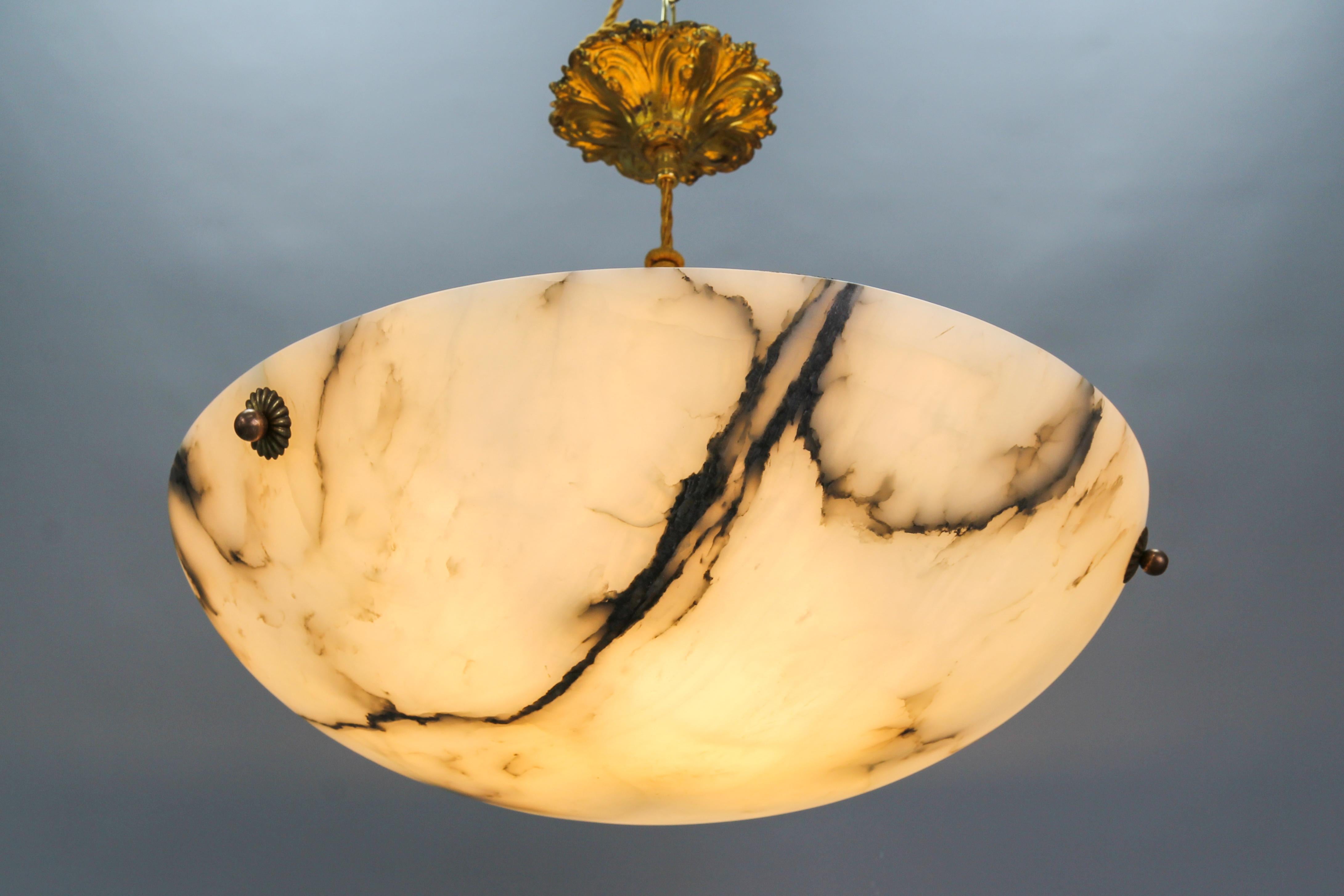 An Art Nouveau period white and black veined alabaster pendant light fixture.
A wonderful alabaster pendant ceiling light fixture from circa the 1920s. Beautifully veined and masterfully carved one-piece white alabaster bowl suspended by three