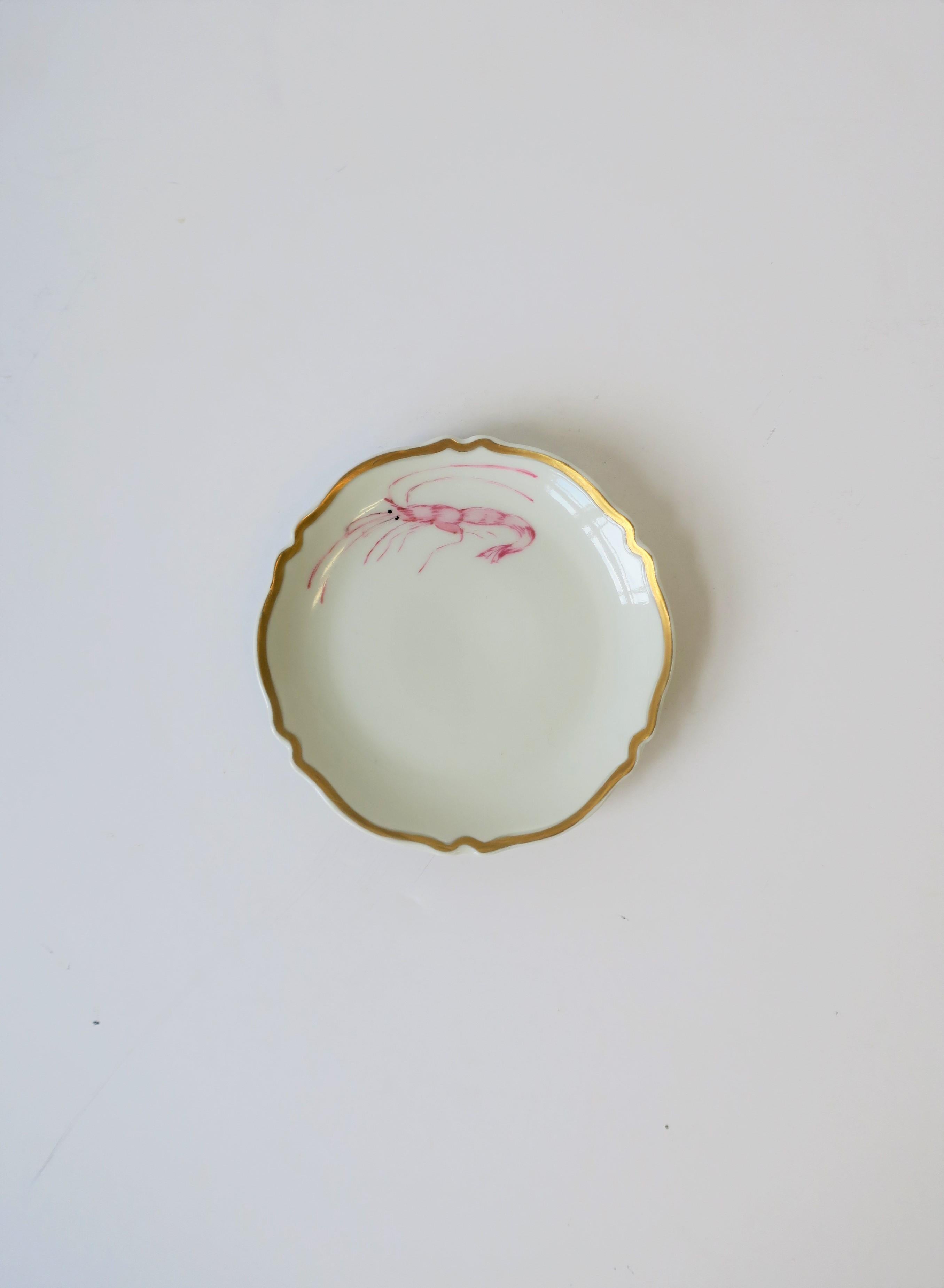 A beautiful midcentury French white and gold round porcelain jewelry dish by Limoges, circa mid-20th century, France. Dish has gold detail around decorative edge and a decorative 'lobster' or 'shrimp' sea creature or crustacean. All hand-painted.