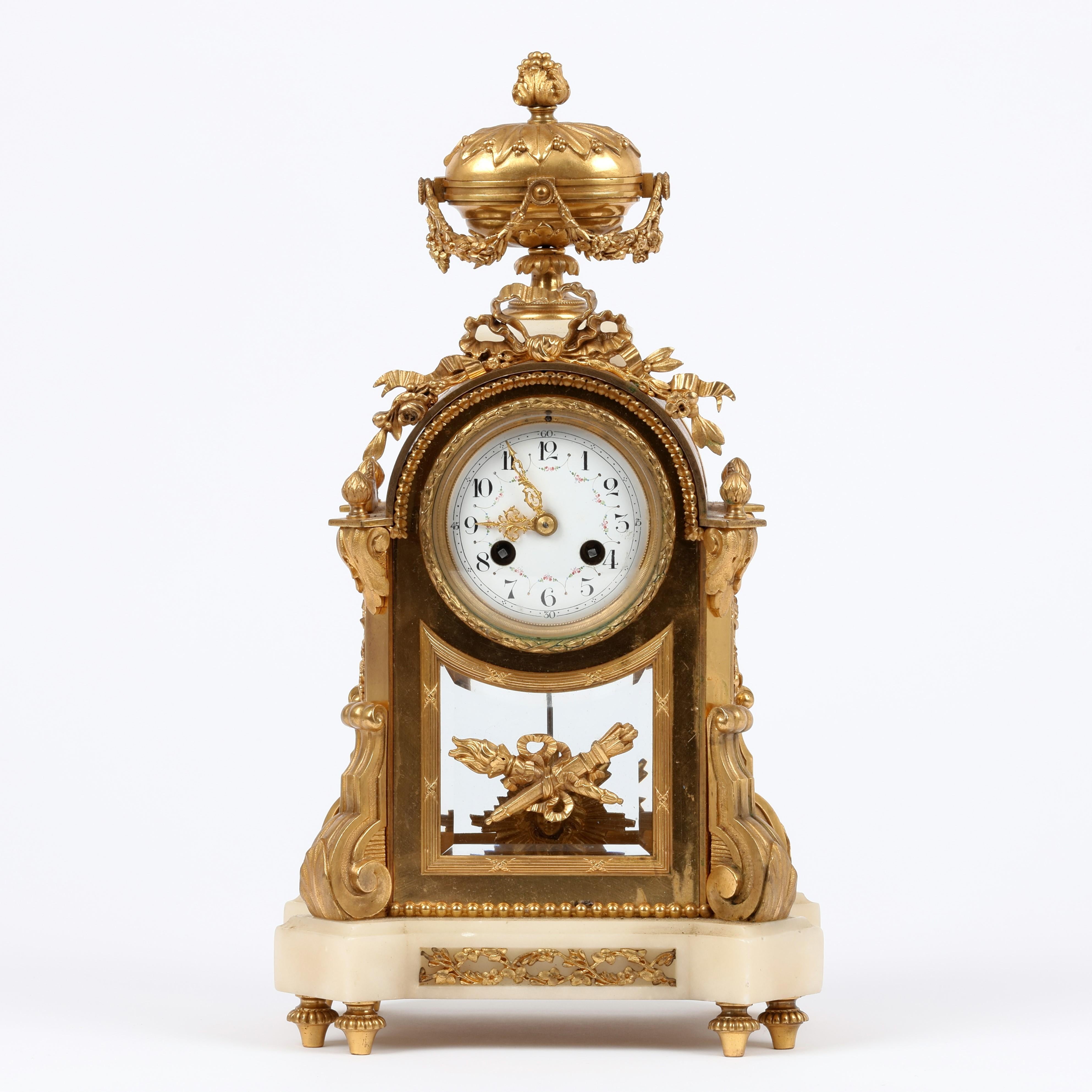 A most attractive small French white marble and ormolu Mantle/Mantel Clock Surmounted by classically shaped lidded urn with flower head finnial and draped all round with floral garlands. The white enamel and hand painted dial is set into the ormolu
