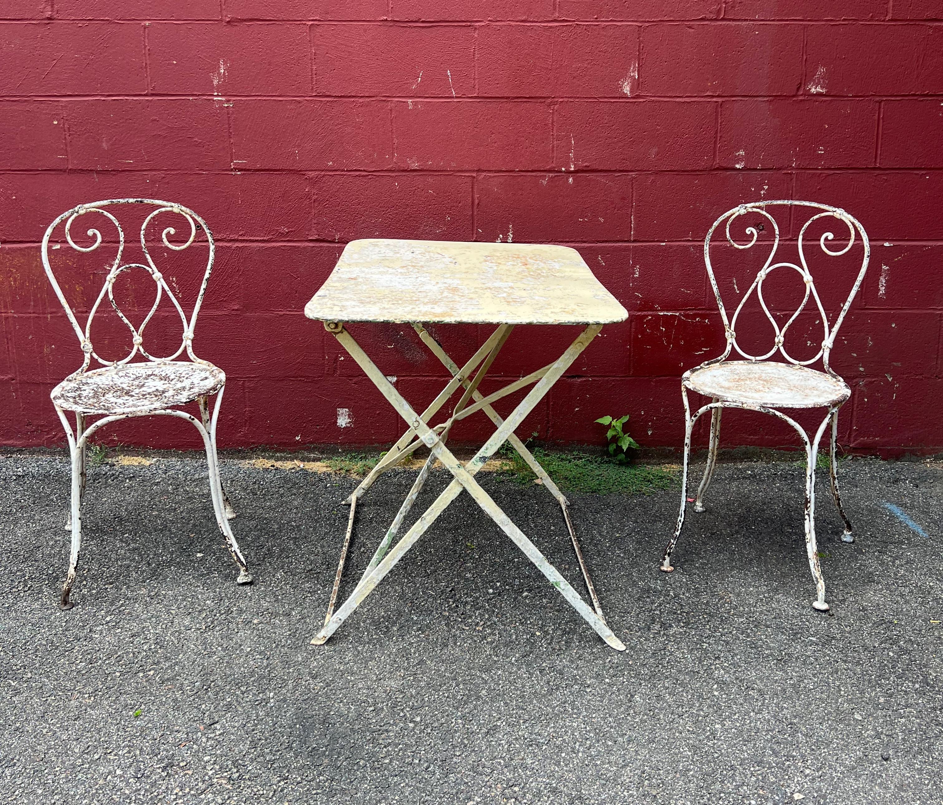 This charming French bistro or garden table in its original distressed white paint is a classic piece that embodies the charm and sophistication of French style. Made of iron and metal, this rectangular table is structurally sound and designed for