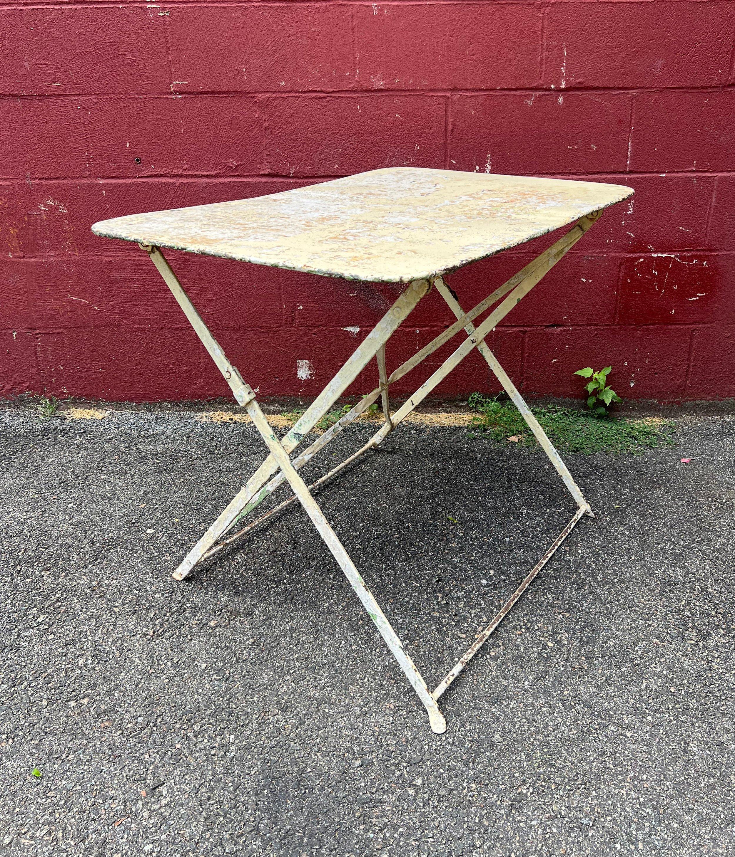 This charming French bistro or garden table in its original distressed white paint is a classic piece that embodies the charm and sophistication of French style. Made of iron and metal, this rectangular table is structurally sound and designed for