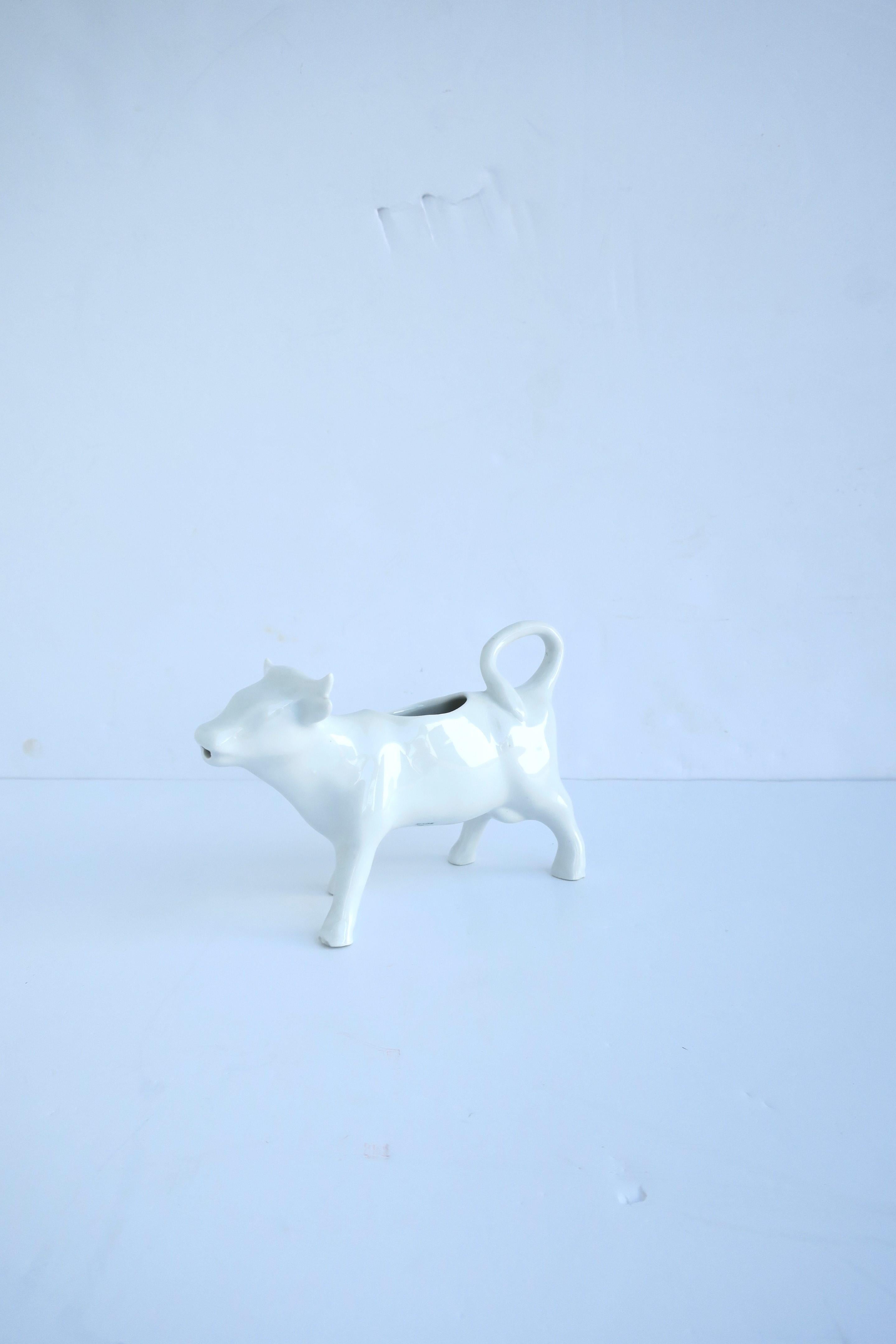 A French white ceramic porcelain cow creamer pitcher in the Rustic style, circa mid-20th century, France. A white porcelain cow creamer pitcher with tail as loop handle. Great as a standalone piece as shown, or for milk, cream, half and half, etc.