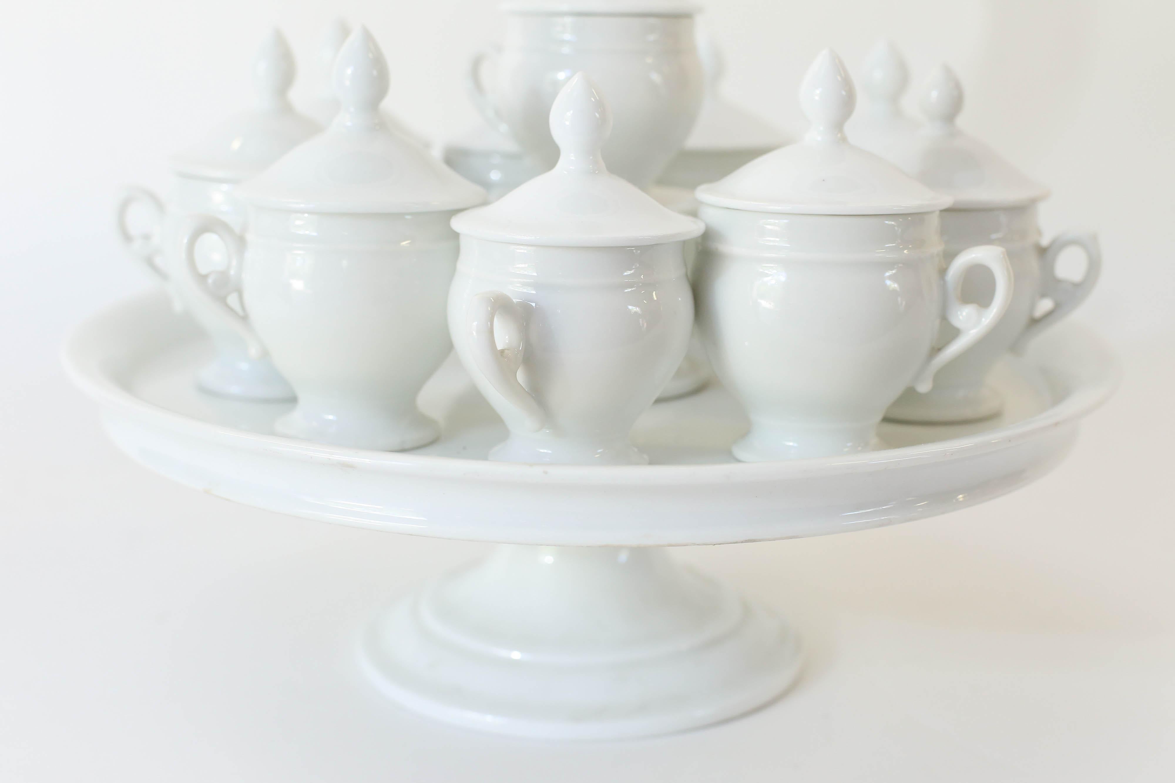Pots de Creme, (cups of cream) tiered Stand and 10 lidded cups in white. These were used to serve desserts of cold custard. This dessert was made in pots, (cups) with their own lids to protect the custard during baking. A beautiful set for a
