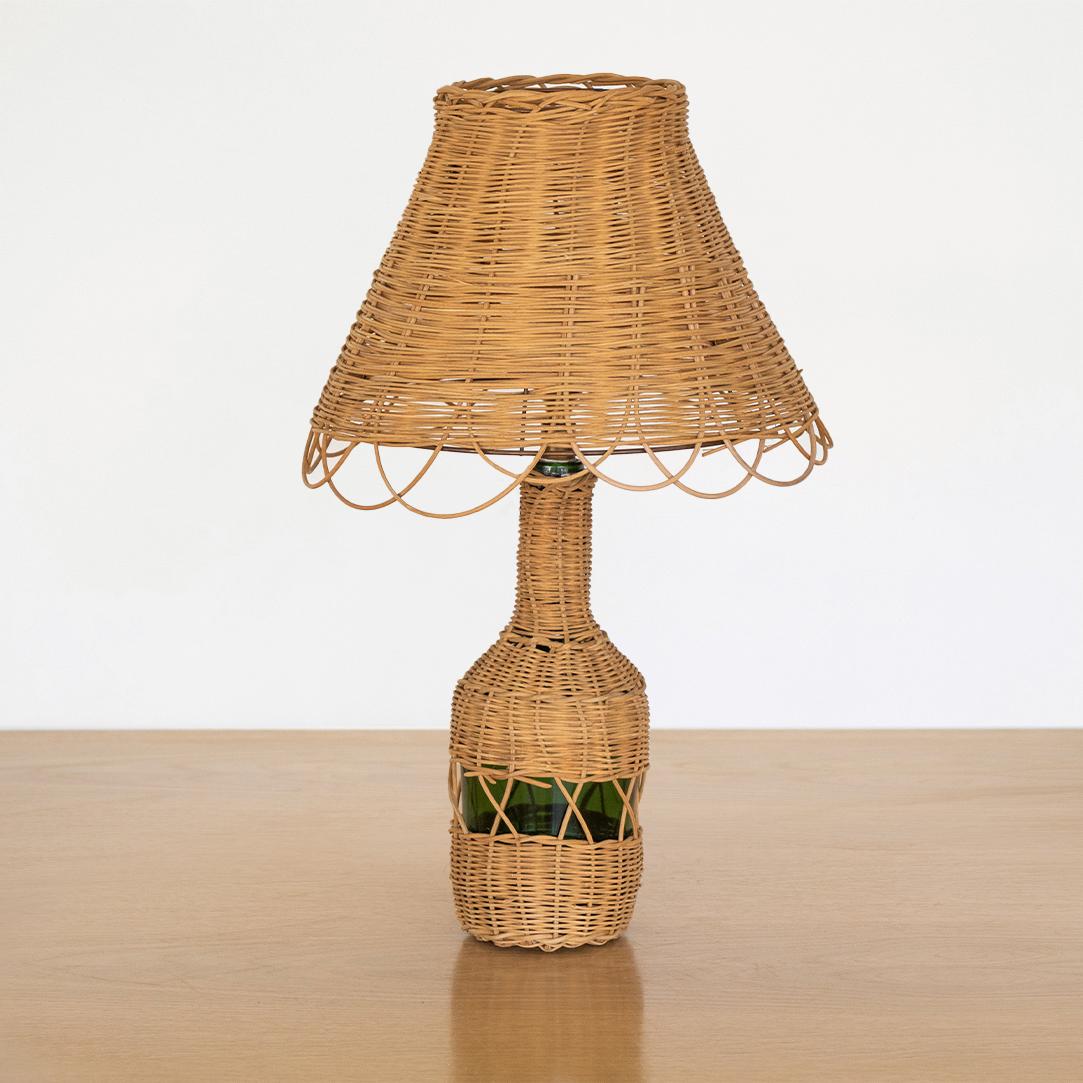 French wicker table lamp with green glass bottle wrapped in wicker. All wicker shade with beautiful scalloped edging.

Measures: Lamp base diameter 4.5