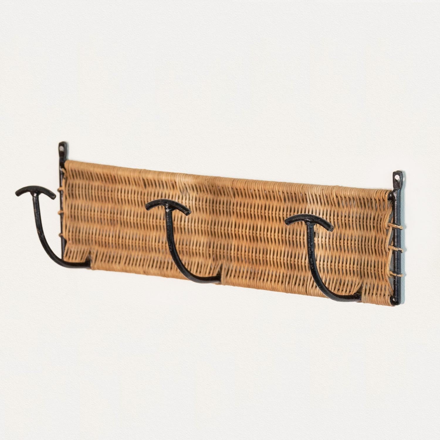 Vintage woven wicker wall rack with 3 iron hooks to hang coats or hats. Black painted iron and wicker is all original. Beautiful and functional piece from France, 1950s. Three available.