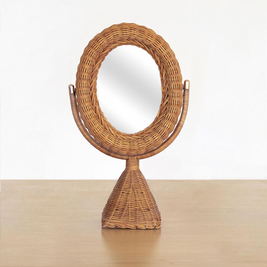Beautiful vanity mirror made of woven wicker from France. Square pedestal base and beautiful wrapped wicker on stand. Oval pivoting mirror with brass detailing.
