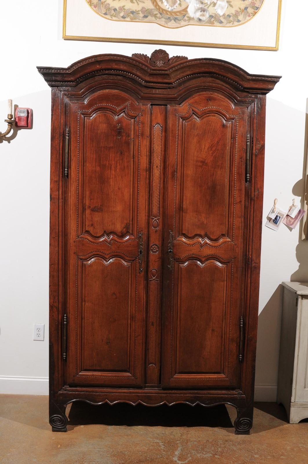 A French late 18th century wild cherry armoire from Rennes, dated 1792 at the cornice. Born in the capital of Brittany, Rennes in the last year of king Louis XVI reign, this French wild cherry armoire features a large double bonnet cornice, accented