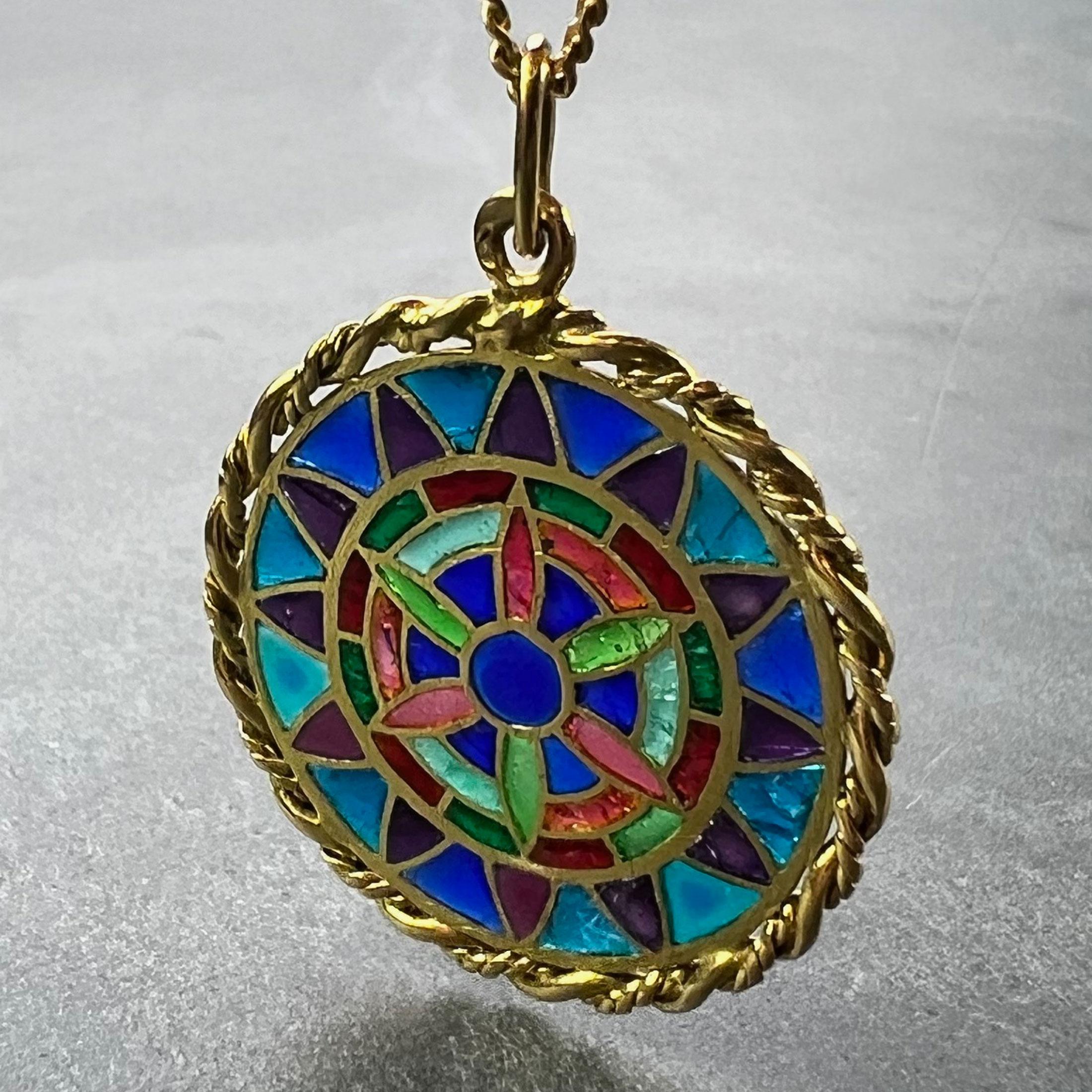 Un ciondolo charme in oro giallo 18 carati (18K) progettato come una medaglia rotonda con un bordo a spirale che raffigura una vetrata in smalto plique-a-jour. Timbrato con il marchio della testa dell'aquila per l'oro a 18 carati e la manifattura