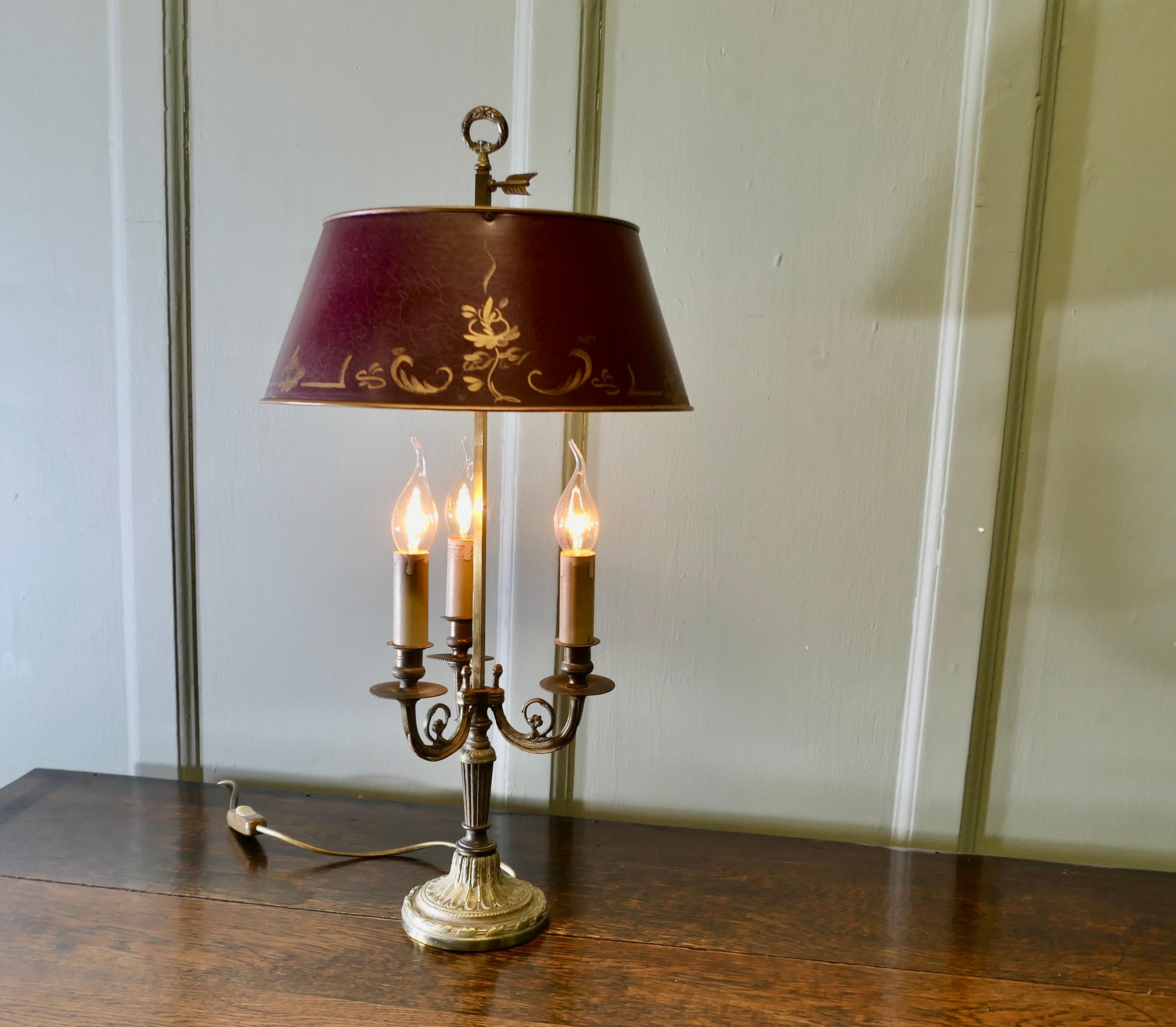 French Wine and Gold Toleware and Brass Triple Desk Lamp

A lovely piece, a brass Triple Bouillotte lamp with its original adjustable toleware shade 
A  Very traditional design with three candles and the arrow shaped grip to adjust the shade 
The