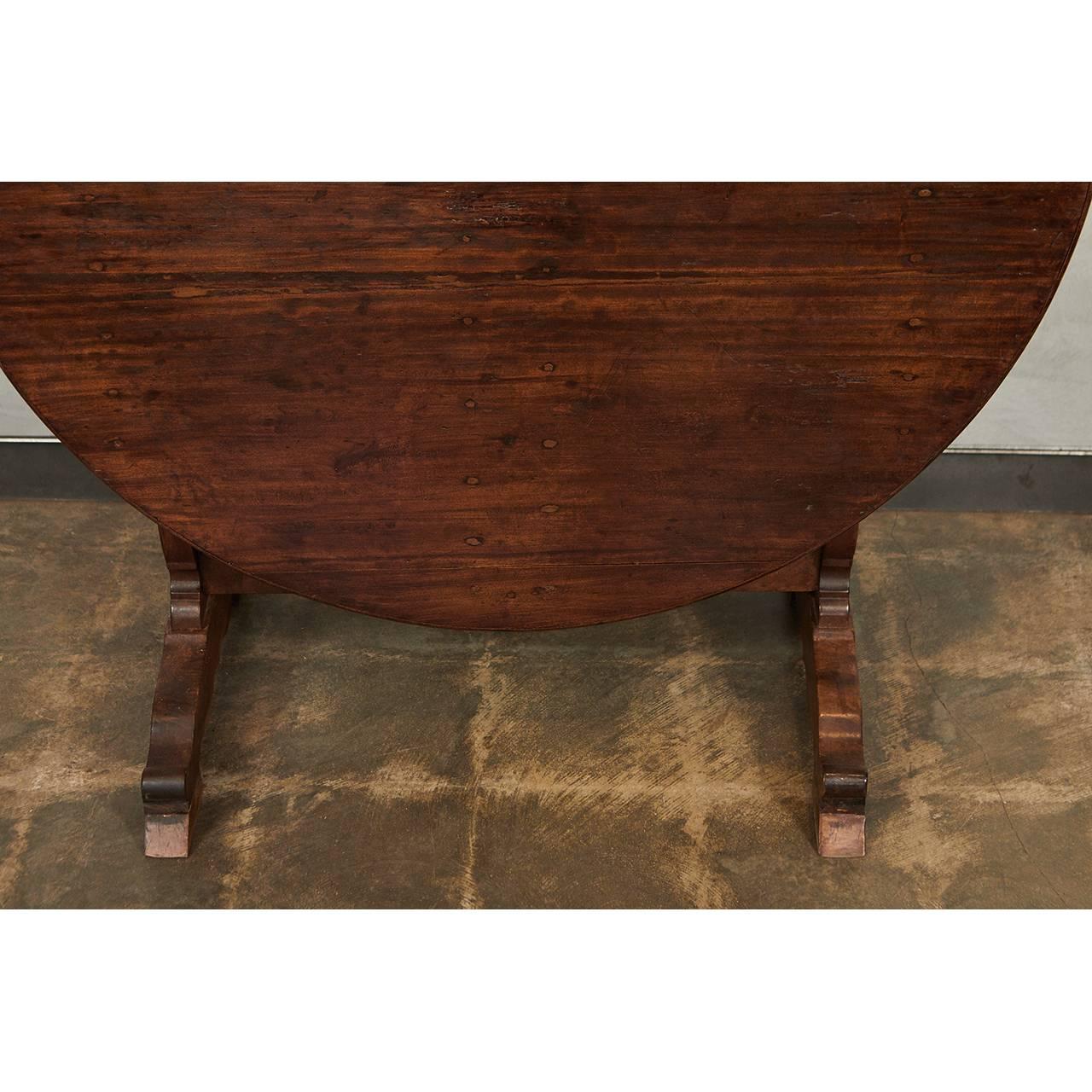 This large French wine table has a round, flip-top with shaped supports and legs and two standing feet. This table's elegant design enables easy storage.
 