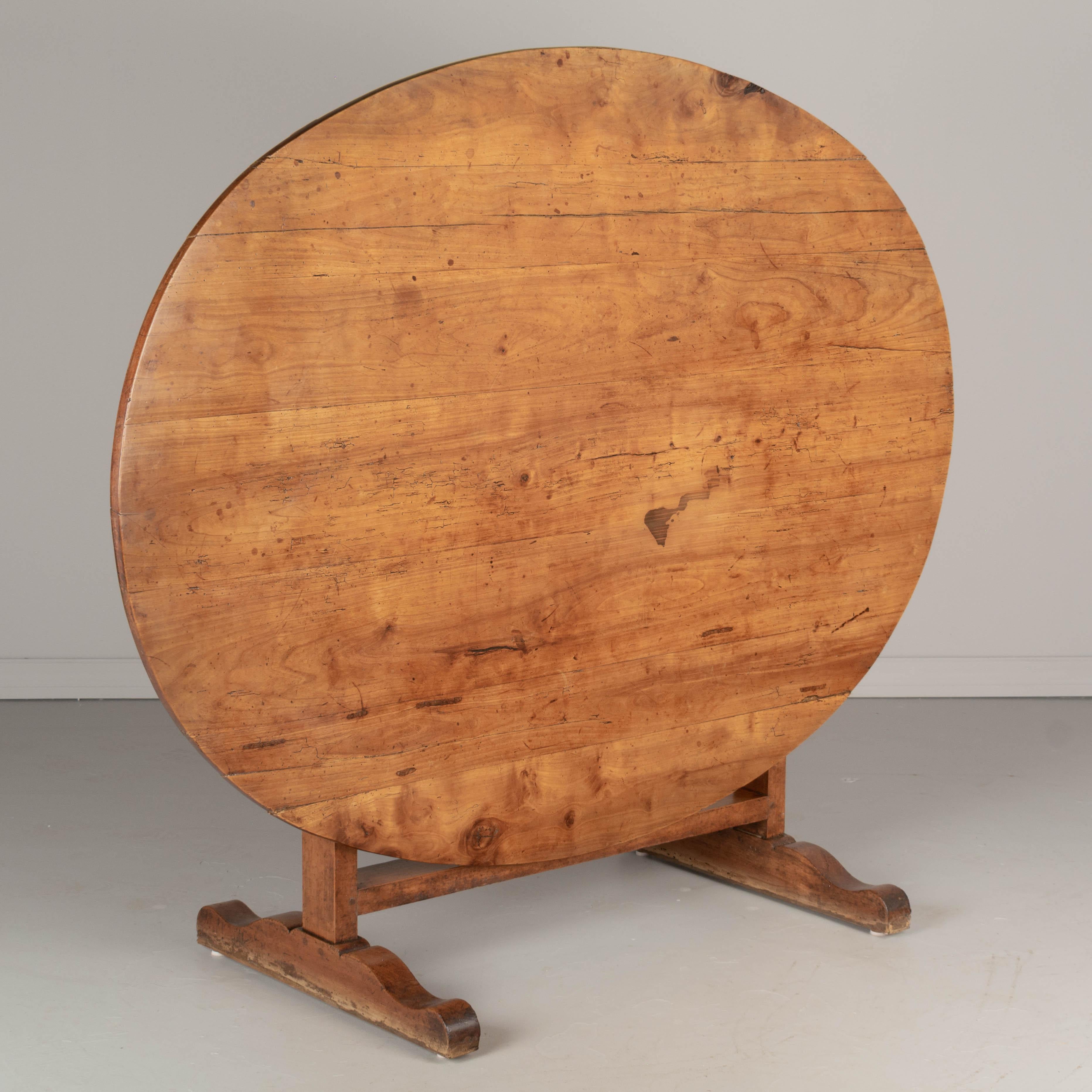 A French Country oval wine tasting table, or tilt-top table, from the Loire Valley. Made of solid cherry wood with thick and sturdy base. Beautiful character to the wood with interesting grain and knots. Well-crafted with mortise and tenon joints