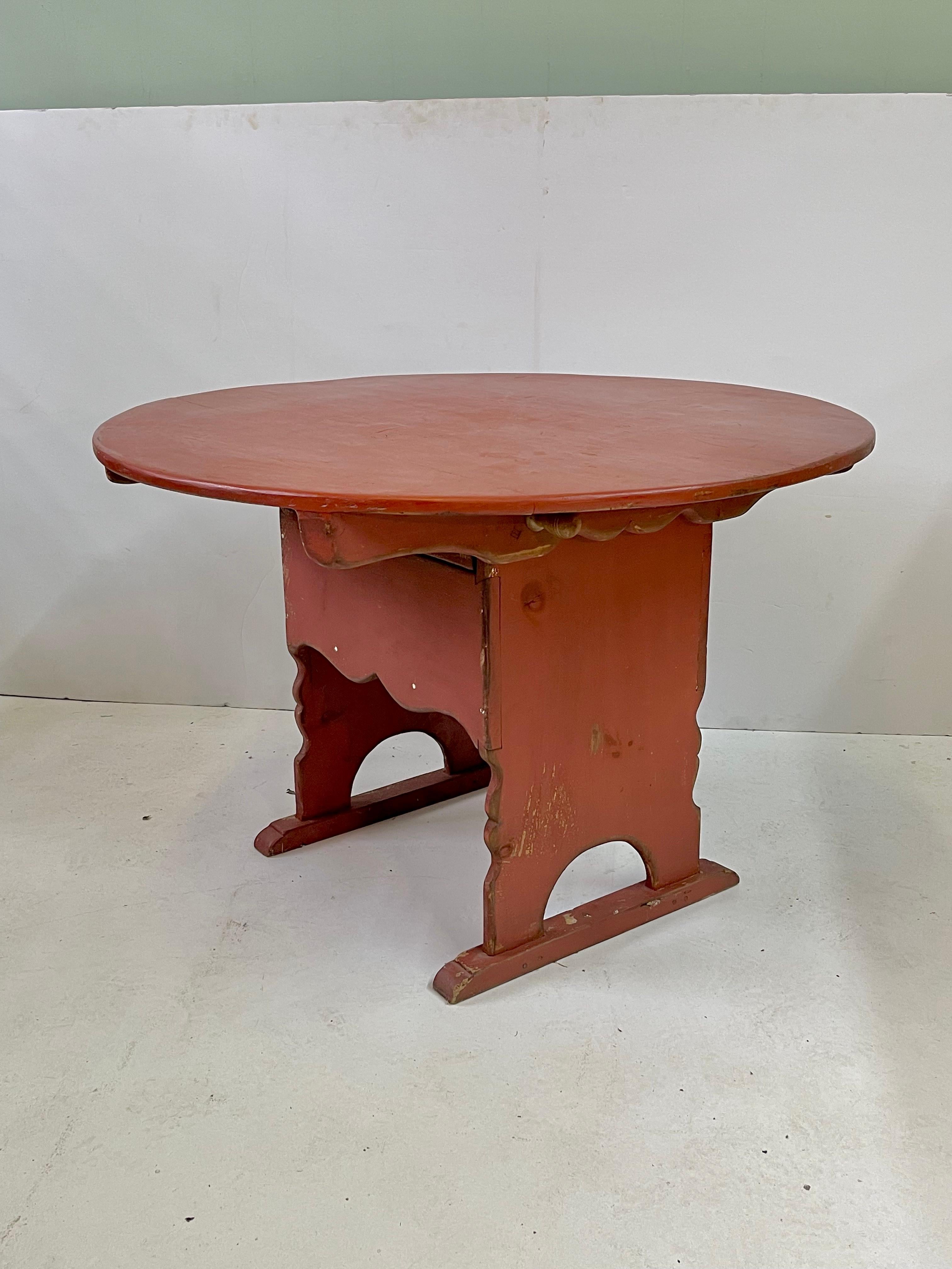 19th Century Provencal French wine tasting table of painted pine on a scalloped trestle base. The tilt top can be opened by releasing wooden dowels to convert the table into a chair with storage in the seat. The table features the original red paint