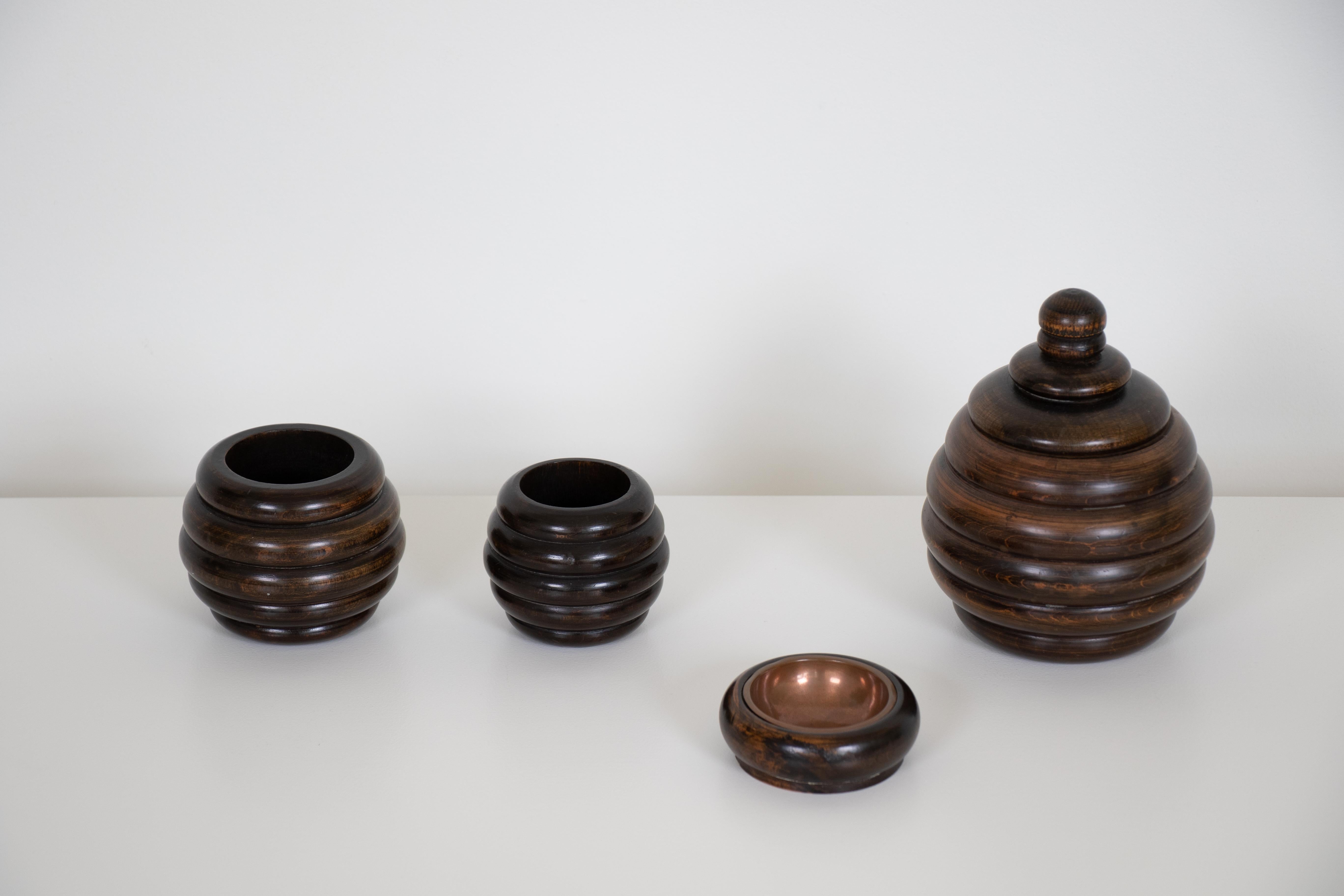 Four-piece set of smoking accessories made of dark oakwood from France. Set consists of two open pots, one larger pot with lid, and one small ashtray/ dish. Could also be used as desk, shelf, or coffee table accessories.

Measures: Large pot with