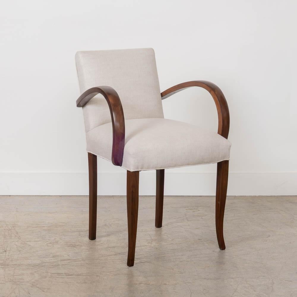 Bellissima poltrona in legno proveniente dalla Francia, anni '50. Seduta imbottita di recente in un bellissimo lino color crema. Braccioli sinuosi in legno intagliato e quattro gambe affusolate. Appena rifinito con una tinta di legno media. Design