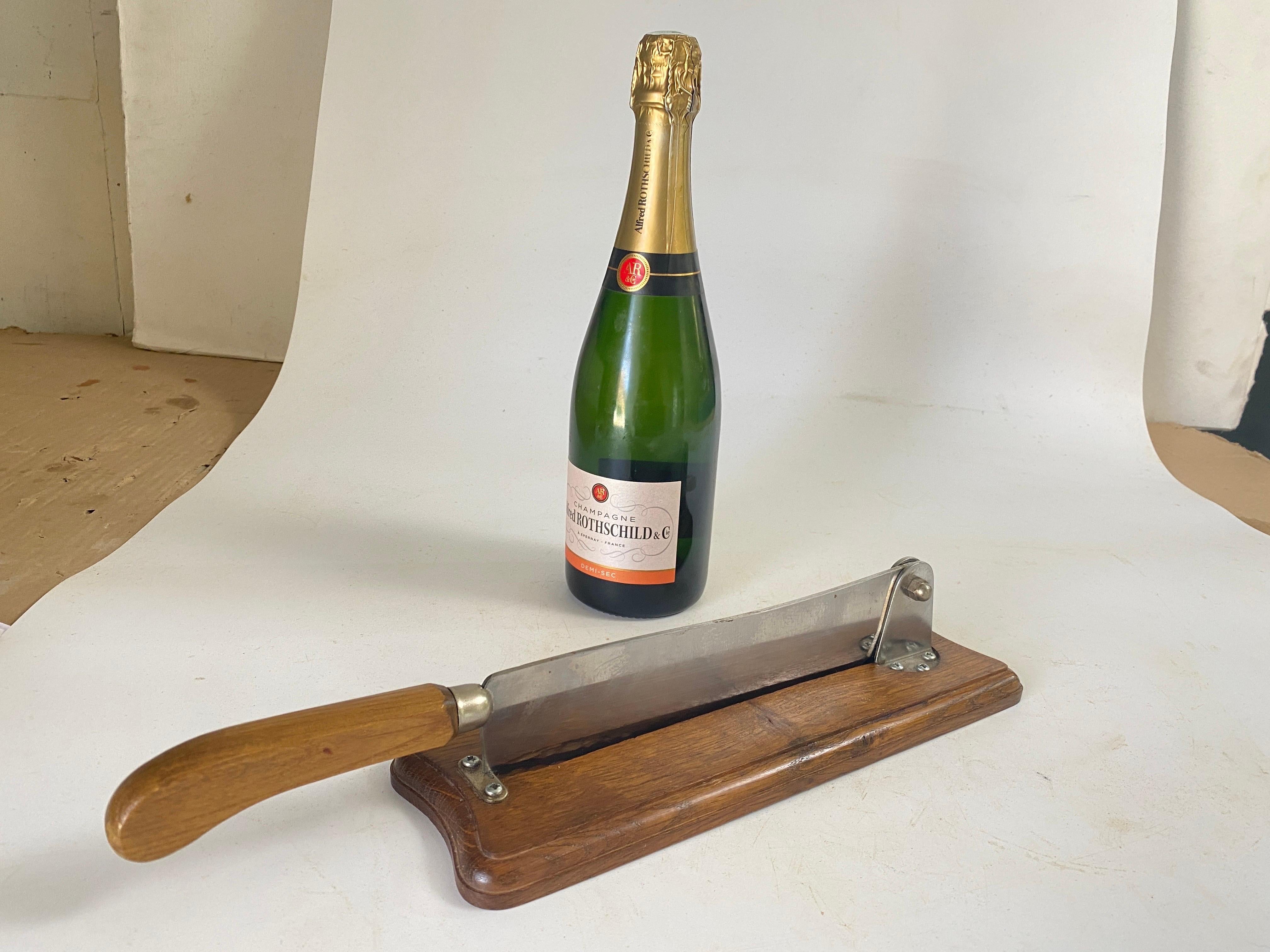 Un couteau à pain sur une plaque en bois patiné, de couleur brune. Le couteau est en acier.
Fabriqué en France au 20ème siècle.
