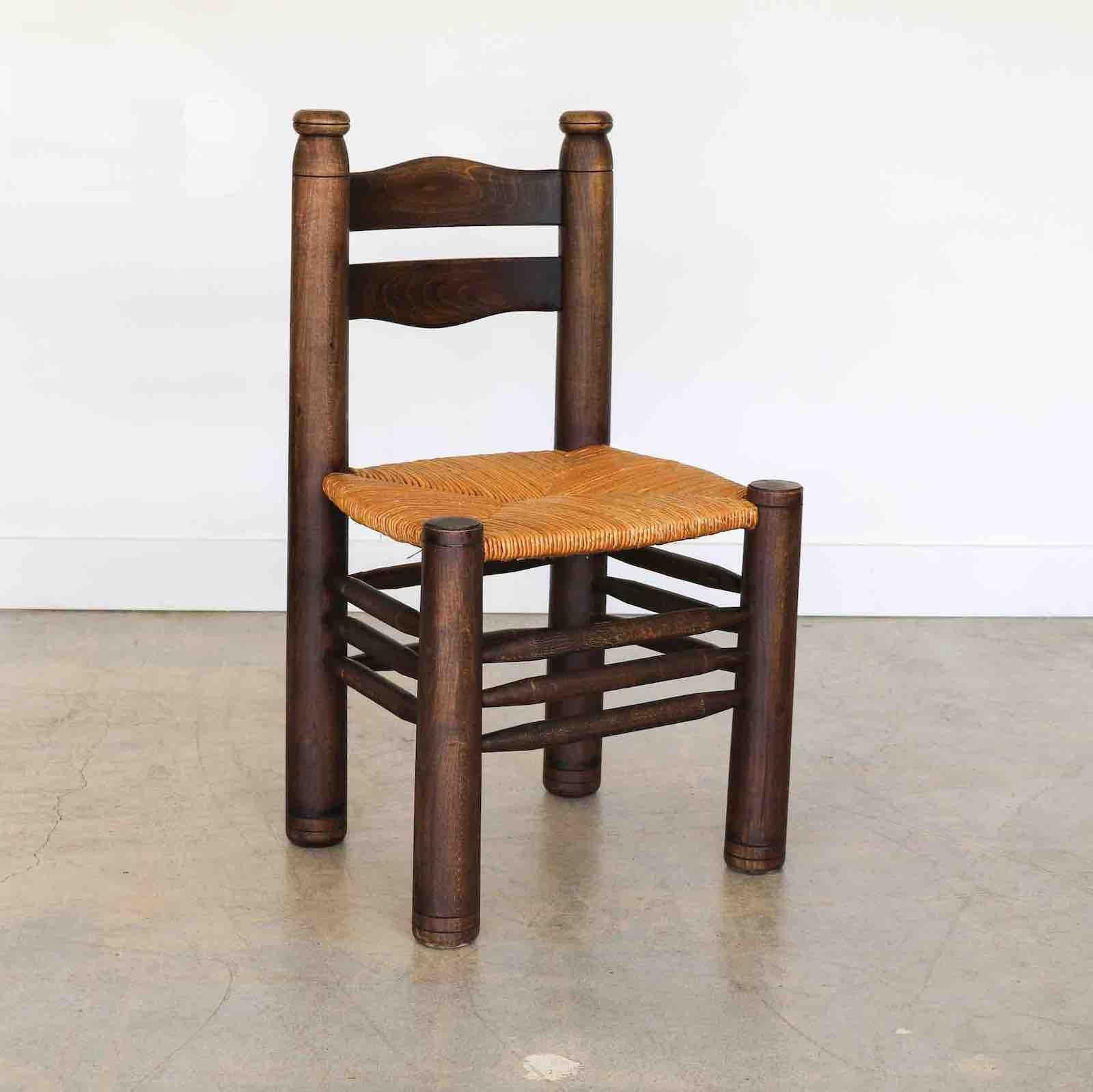 Incroyable chaise en bois et tressage de Charles Dudouyt en France dans les années 1940. Pieds fuselés solides et épais avec un magnifique dossier en bois sculpté et ondulé. Siège en jonc tissé d'origine. La teinture d'origine du bois foncé est en