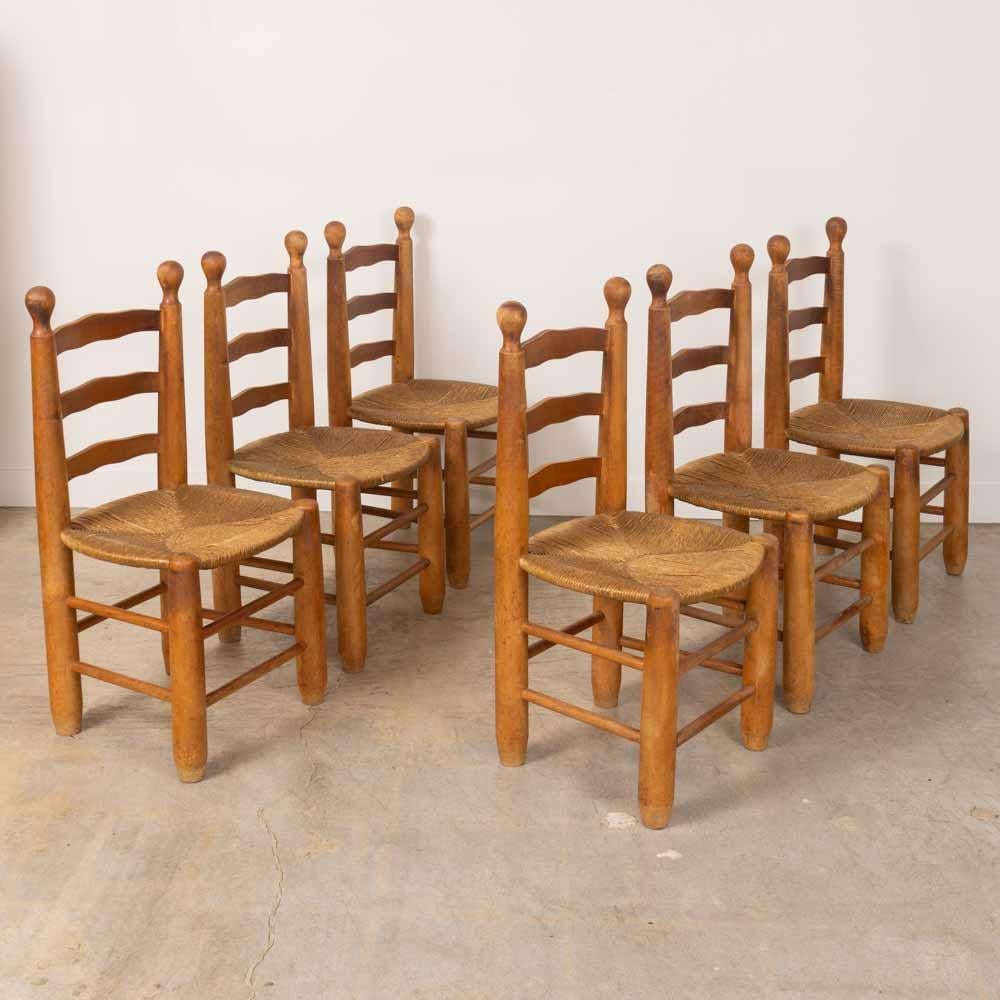 Increíble conjunto de seis sillas de madera y tejido de Charles Dudouyt, Francia, años 50. Sólidas y gruesas patas cónicas con hermosos respaldos de madera tallada ondulada y grandes detalles de bolas de madera. Asientos originales de junco tejido