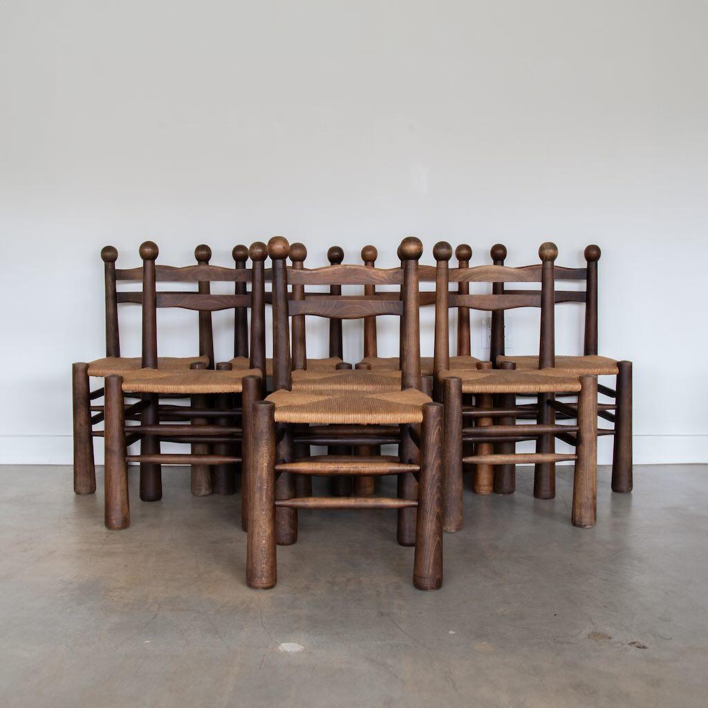 Incredible rare set of 8 wood and woven chairs by Charles Dudouyt from France 1940's. Solid and chunky tapered legs with beautiful wavy carved wood backs and large wood ball details. Newly woven rush seats. Dark wood is in vintage condition with