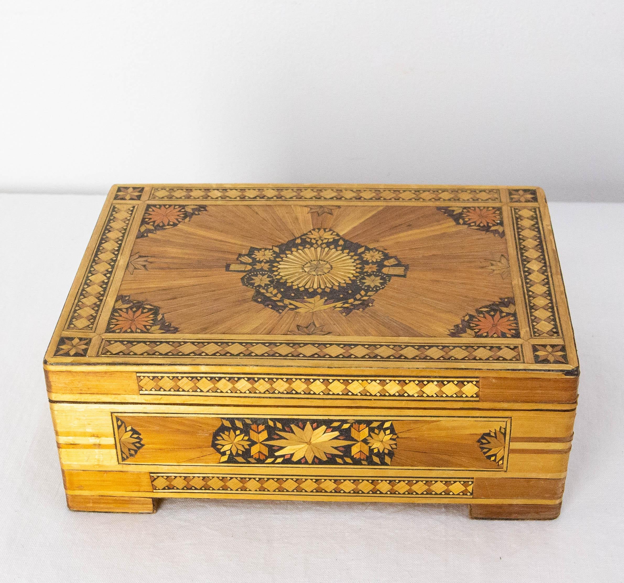Coffret en bois français décoré d'une marqueterie comprenant des étoiles et des motifs géométriques.
La marqueterie de paille était une technique courante au début du 20e siècle. La paille était teintée de différentes couleurs pour créer de riches