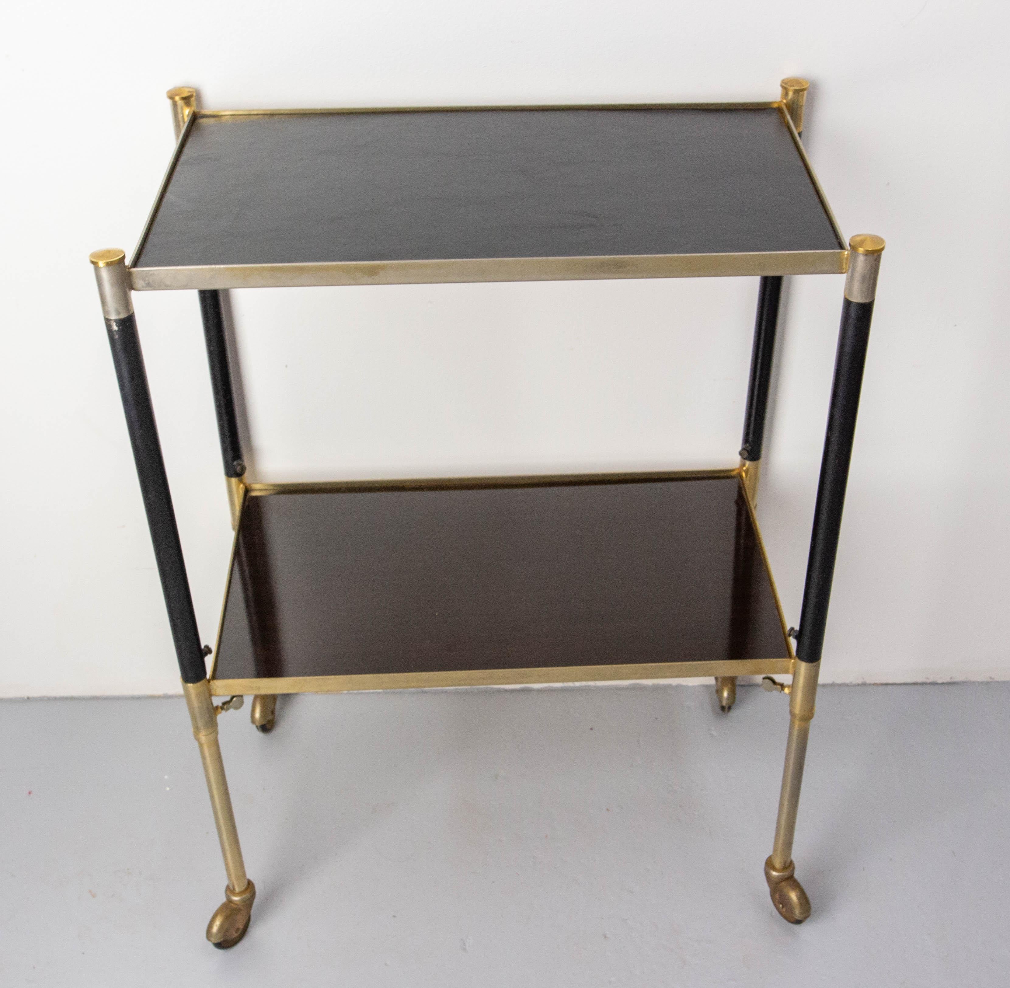 Vintage wood, leather and brass dessert trolley, height adjustable.
The top tray is recovered of natural leather, and the low tray is in wood recovered of a polyester varnish 
Characterful marks of use.
French, circa 1960.
Delivered