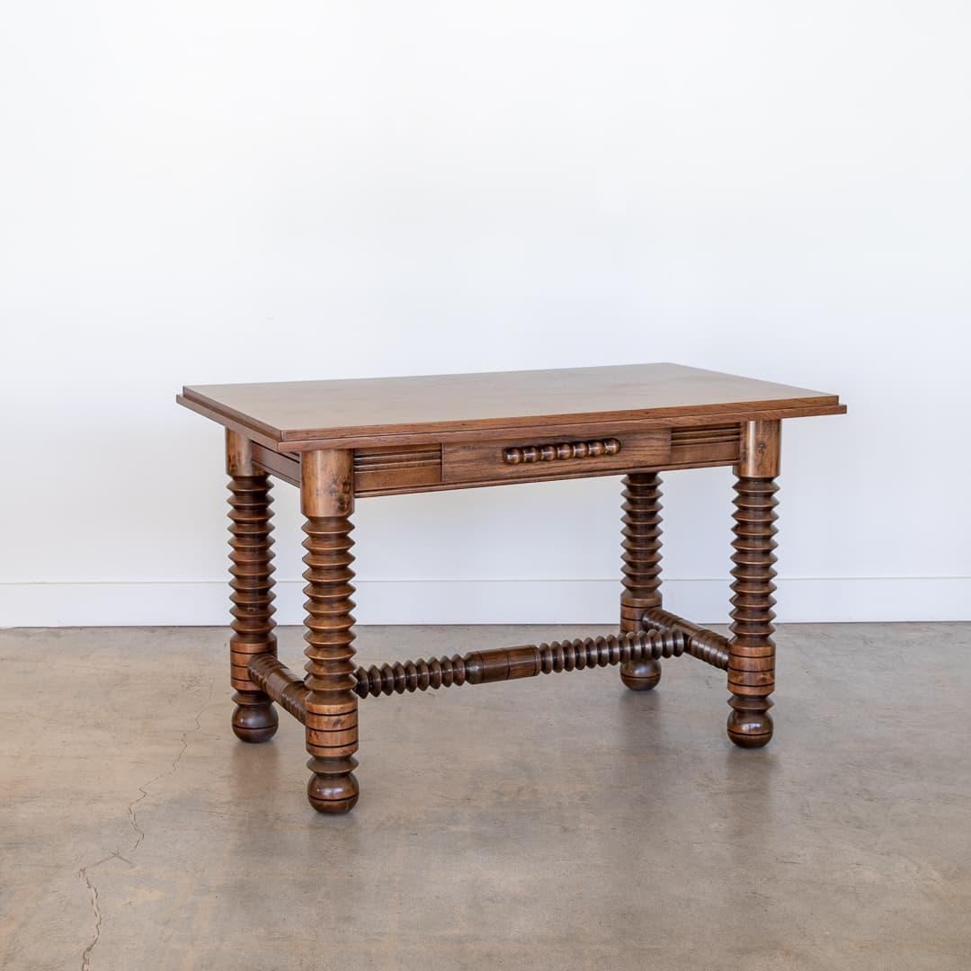 Incredible wood desk by Charles Dudouyt, made in France, 1940's. Large rectangular top with four thick carved wood legs and ball feet. Beautiful wavy knob detail on single pull out drawer. Newly refinished in medium color showing nice grain in wood.