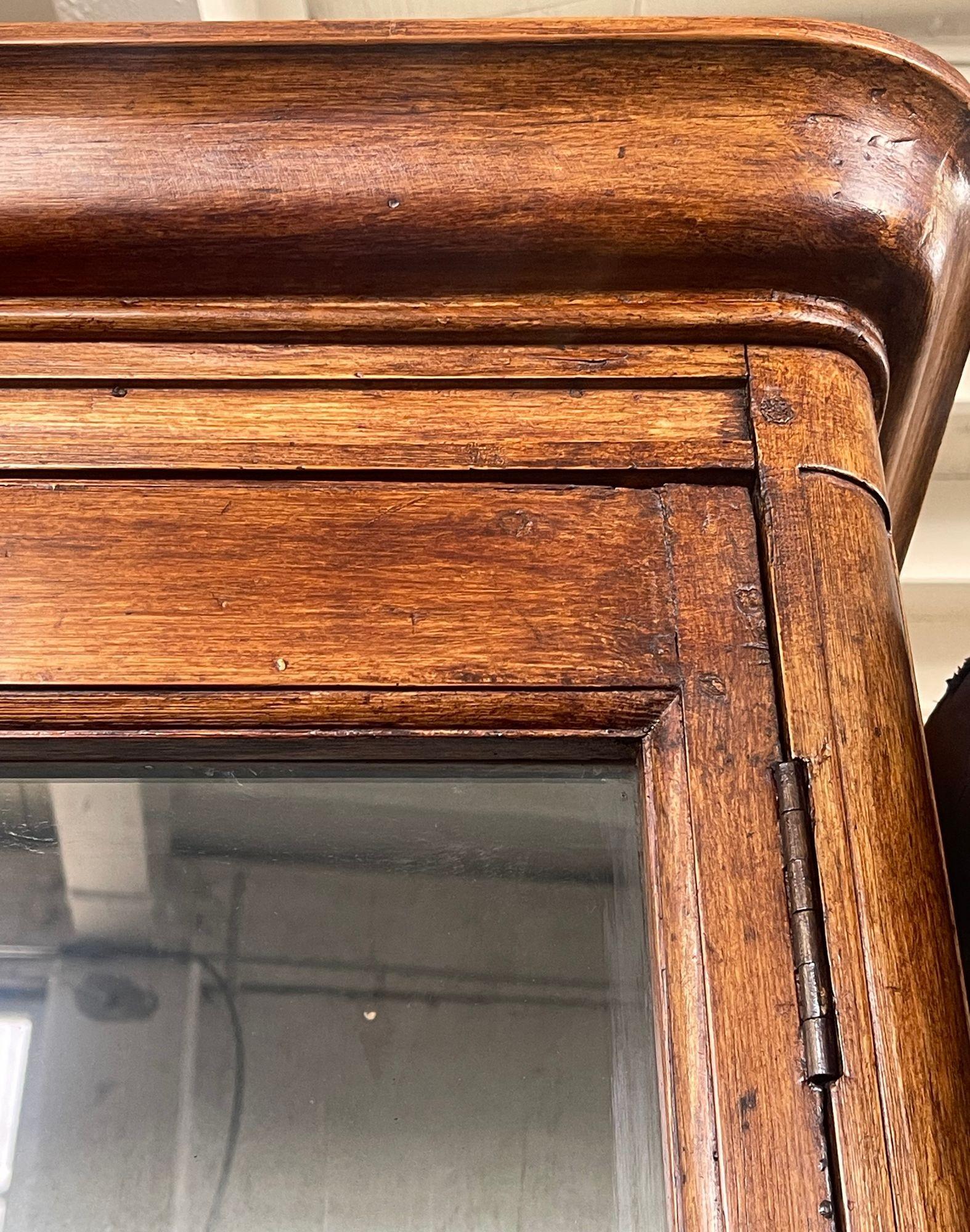 Elegante französische Vitrine aus dem 20. Jahrhundert mit einem warmen Holzrahmen, zwei Glastüren und fünf Glaseinlegeböden. Der Innenraum ist in einem sanften Blauton gestrichen, der einen subtilen Kontrast bildet und die ausgestellten Gegenstände