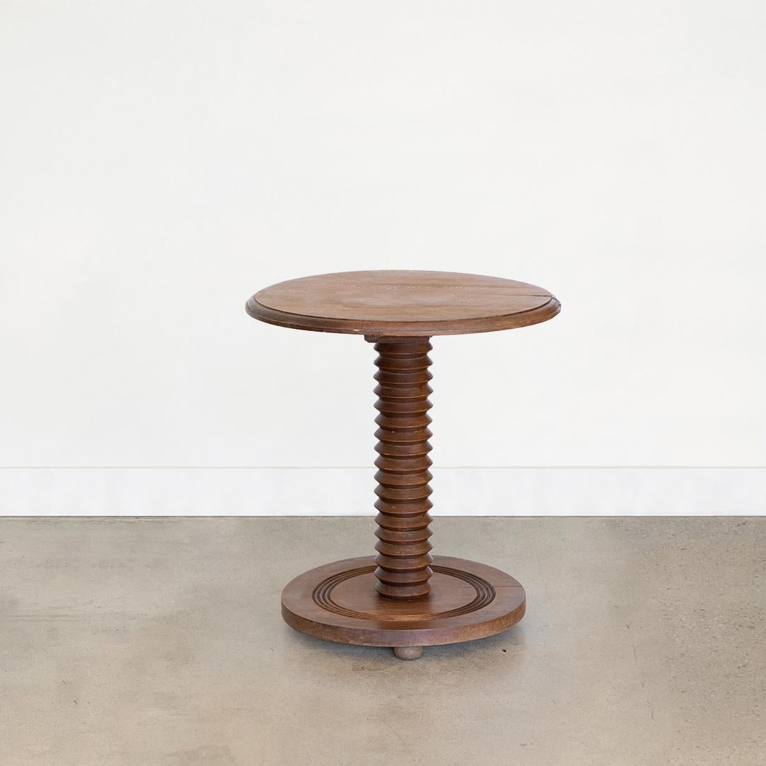 Belle table guéridon en bois sculpté dans le style de Charles Dudouyt, fabriquée en France, années 1940. Plateau circulaire avec tige en bois sculpté et base circulaire. Finition en bois d'origine présentant de belles marques d'âge et une belle