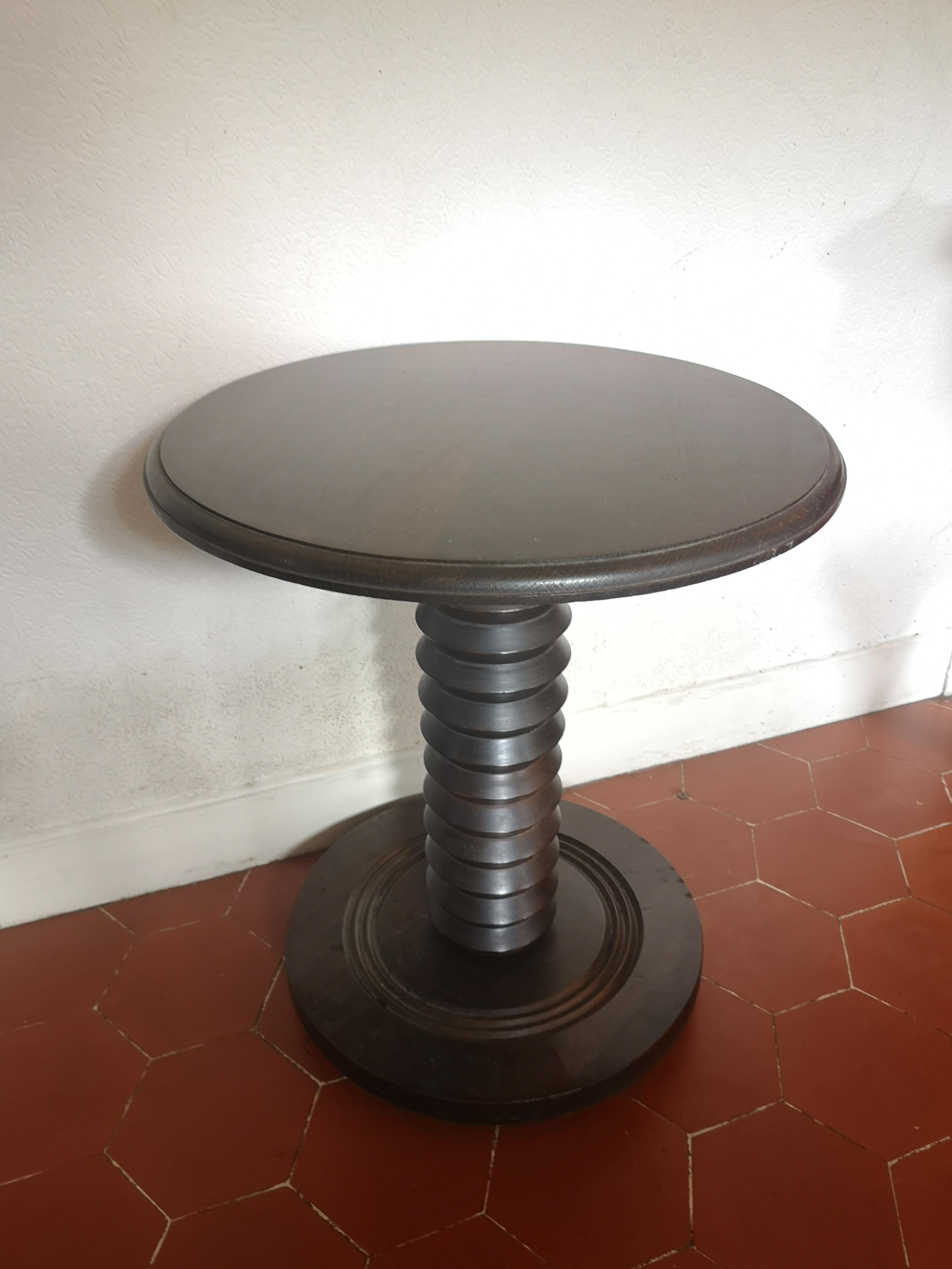 Beautiful carved wooden pedestal table in the style of Charles Dudouyt, 1940s. Circular top with carved wooden rod and circular base. nice dark patina

A favorite among Art Deco furniture collectors and enthusiasts, the work of Charles Dudouyt is