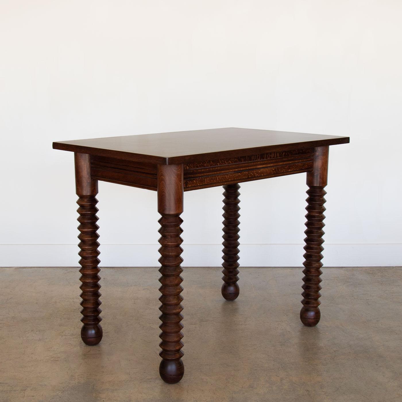Great wood table by Charles Dudouyt, made in France, 1940's.  Rectangular top with four thick carved wood legs and ball feet. Newly refinished in dark stain showing nice grain in wood and newly replaced veneer top. Perfect as a small desk or console