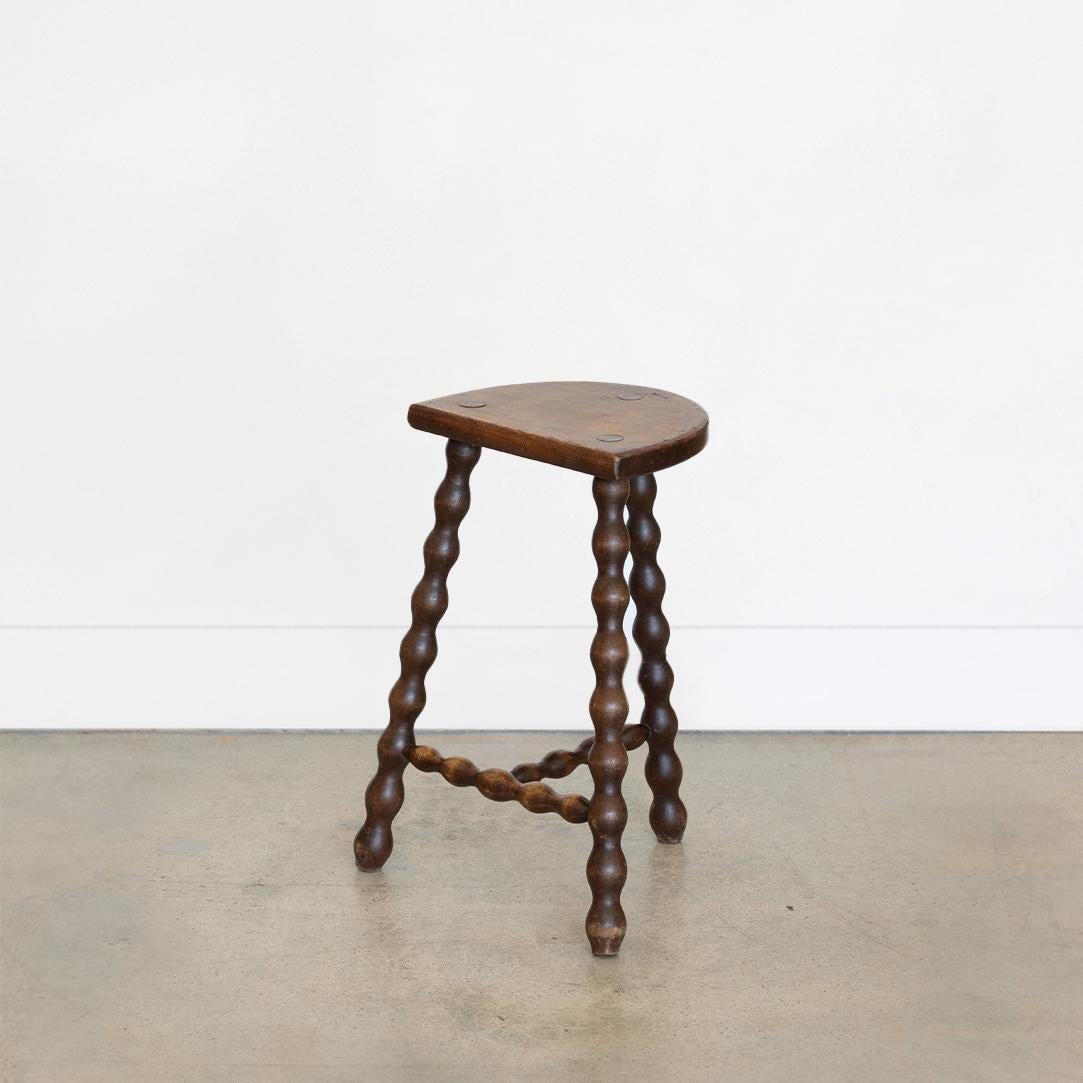 Vintage tall wood stool with semi-circle seat and wavy tripod legs from France. Original wood finish with great age markings and patina. Can be used as a stool or as side table. 



 