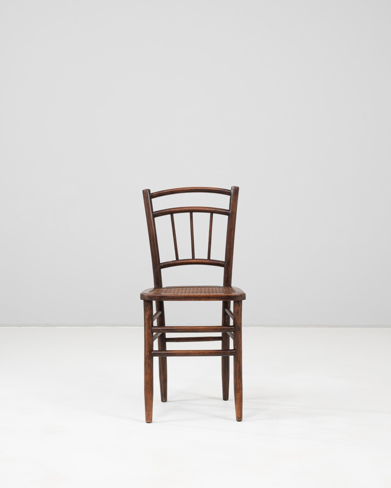 This French wooden chair reflects the timeless appeal of traditional craftsmanship with its simple, elegant form and warm patinated finish. The gently curved backrest features a ladder-style arrangement with vertical slats and two arched supports,
