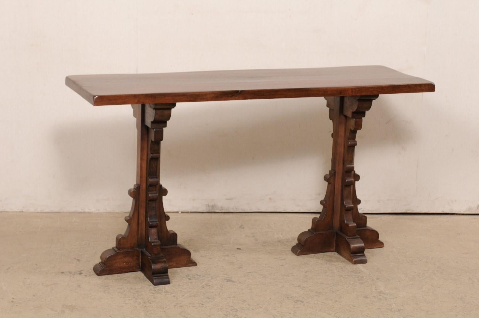 A French fruitwood console table with unusual legs. This contemporary table from France features a rectangular-shaped top comprised of a single board, which is supported by a pair of fabulous legs, each adorn on all four sides in stylized c-scrolls