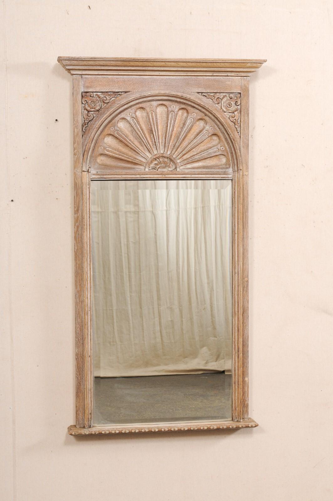 Grand miroir trumeau en bois sculpté, à motif d'éventail, du début du 20e siècle. Ce miroir ancien de France présente un sommet à crête moulée, au-dessus d'un panneau traditionnel de style trumeau, sculpté d'un motif d'éventail (ou peut-être des