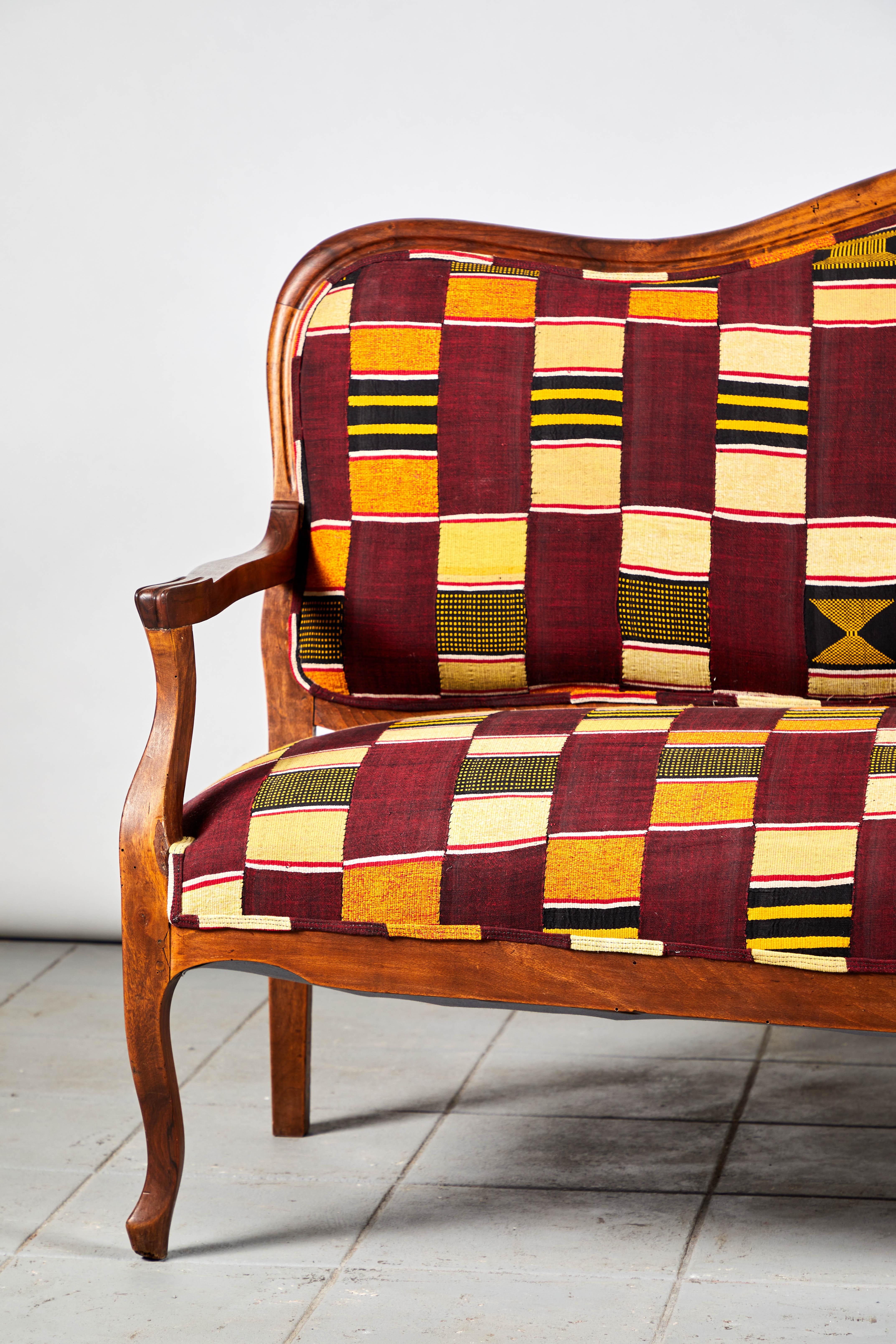 Beautifully constructed French framed camelback bench upholstered in a one of a kind vintage Ewe fabric from Ghana. The fabric is beautifully handmade with a colorful patchwork pattern.
