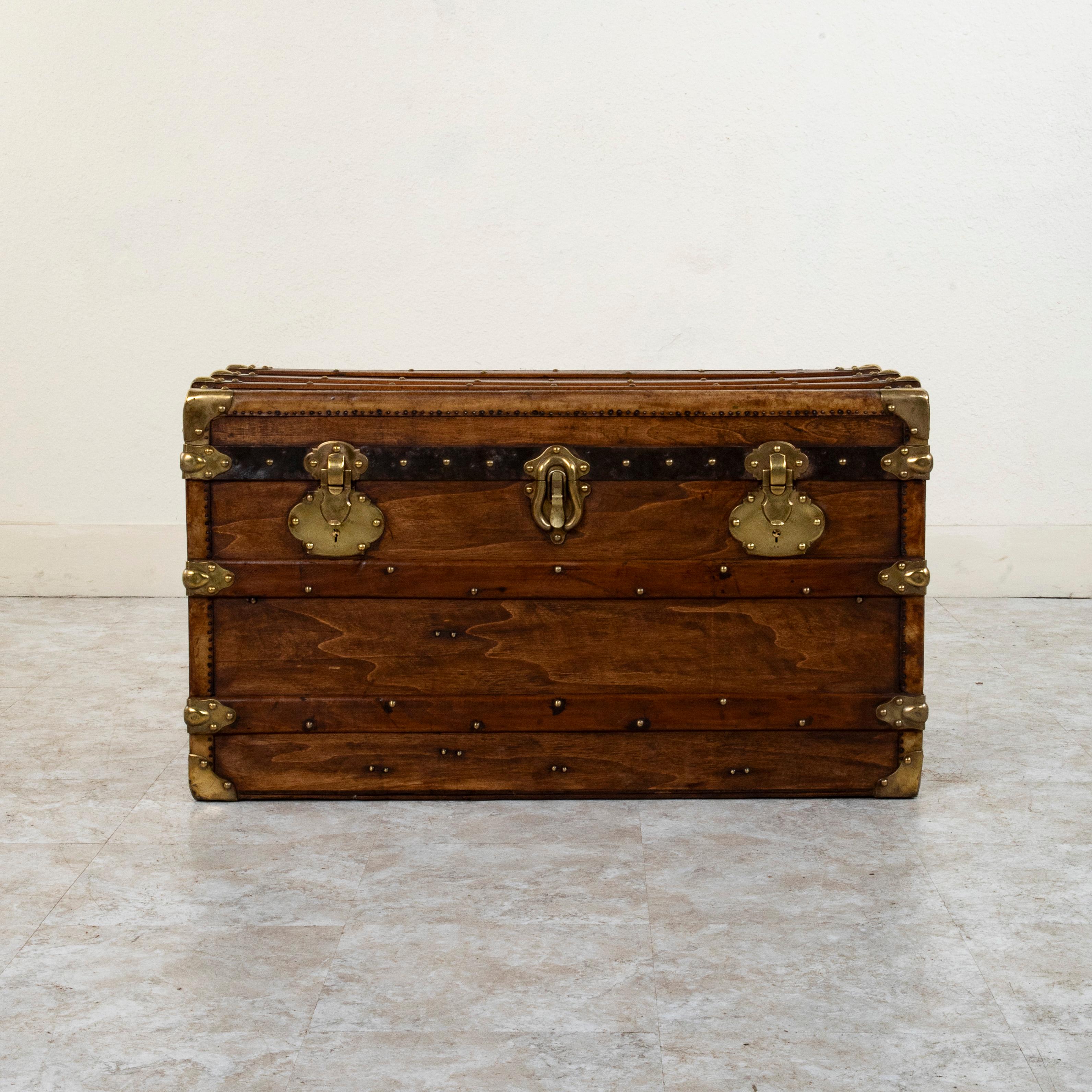 This French wooden steam trunk from the late nineteenth century features locks stamped Surete and Brevete S.G.D.G. Its wooden runners with brass rivets and brass corners offered protection from damage when traveling, and its original leather handles