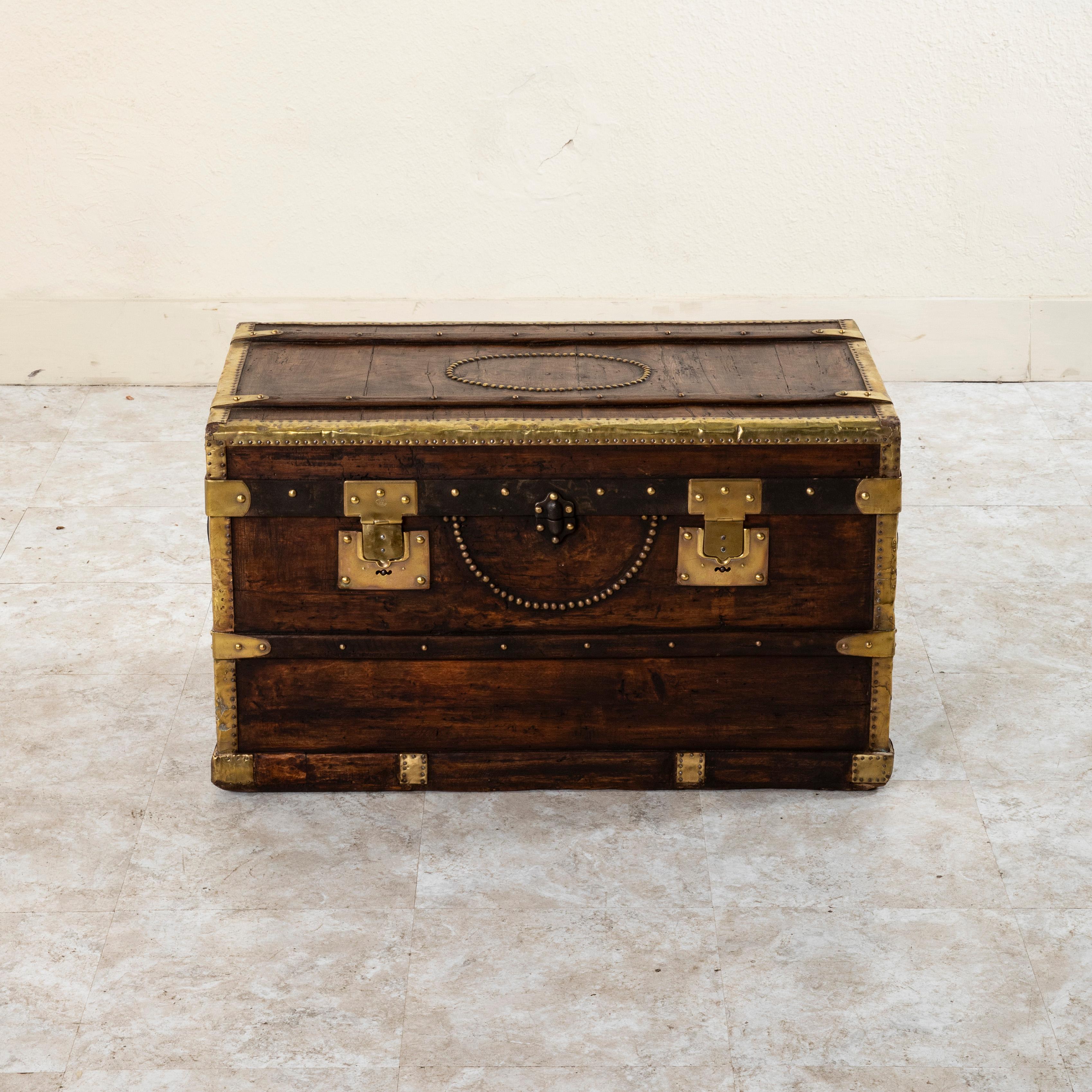 This French wooden steam trunk from the late nineteenth century features locks stamped by the maker D. Jne, Brevete S.G.D.G. Its wooden runners with brass rivets and brass corners offered protection from damage when traveling, and its original