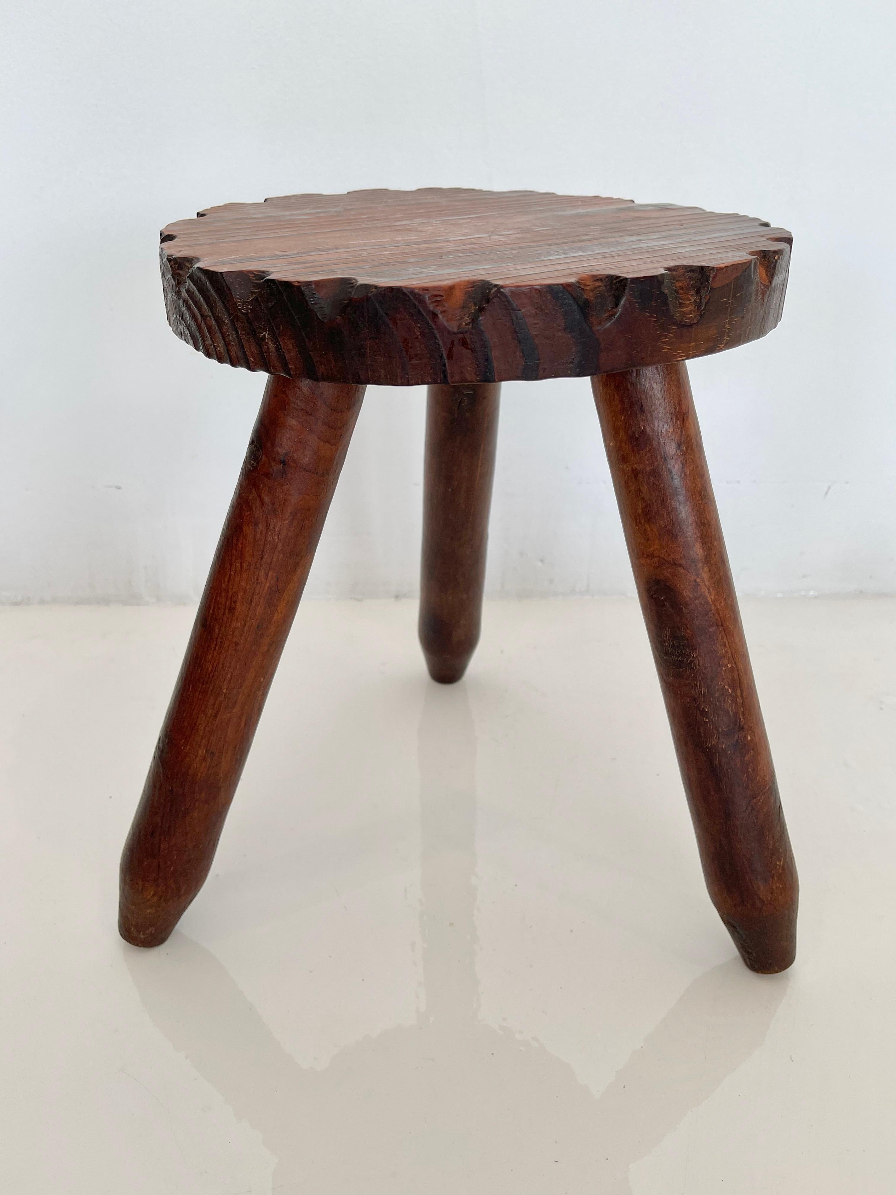 Unusual wood tripod milking stool made in France, circa 1950s. Great patina to wood with scalloped notches around seat and three thick legs. No nails or hardware. Petite stool with great presence. Good vintage condition.