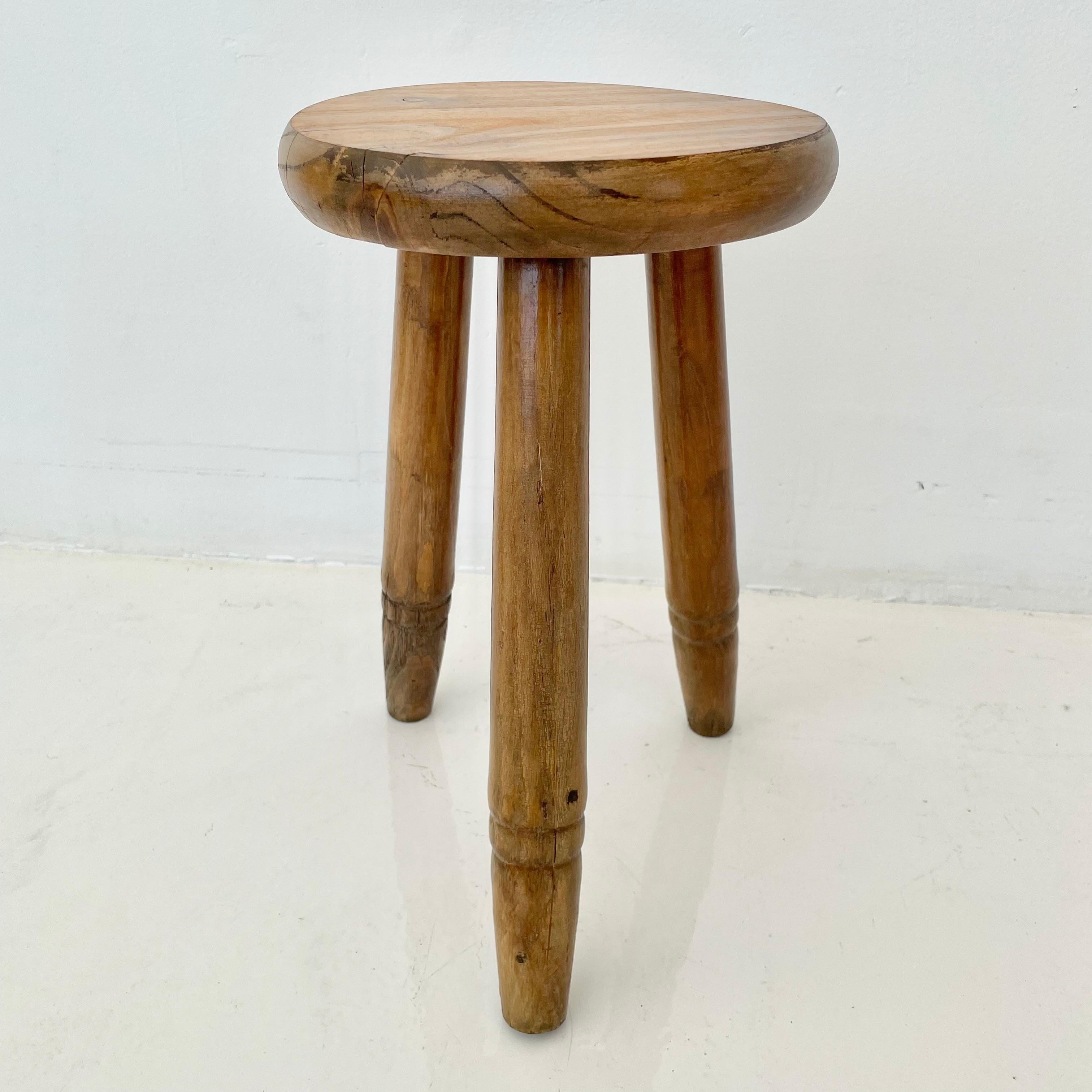 Vintage-Holzhocker, hergestellt in Frankreich, ca. 1950er Jahre. Dicker Sitz und dreibeinige Beine mit Rippen, die sich nach unten hin verjüngen. Keine Nägel oder Beschläge. Großartige Linien und Formen. Rustikaler, zierlicher Hocker mit viel